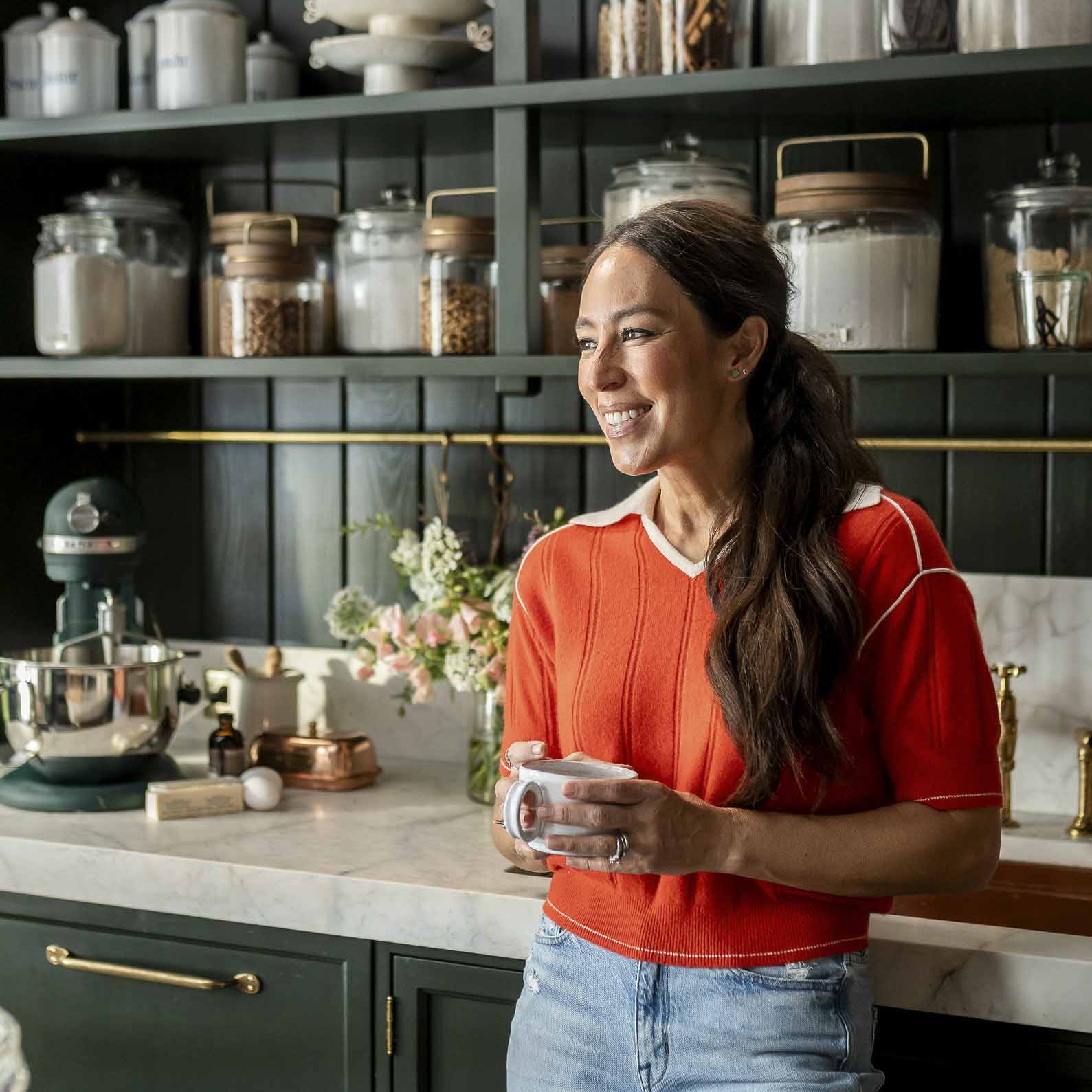Joanna Gaines holds a cup of coffee in her butler's pantry at the farm—surrounded by cookies and baking essentials.