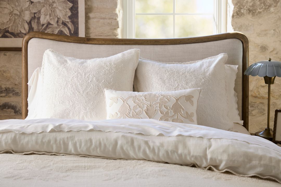 shop bedding. Image features a bed made with quilts and pillows.