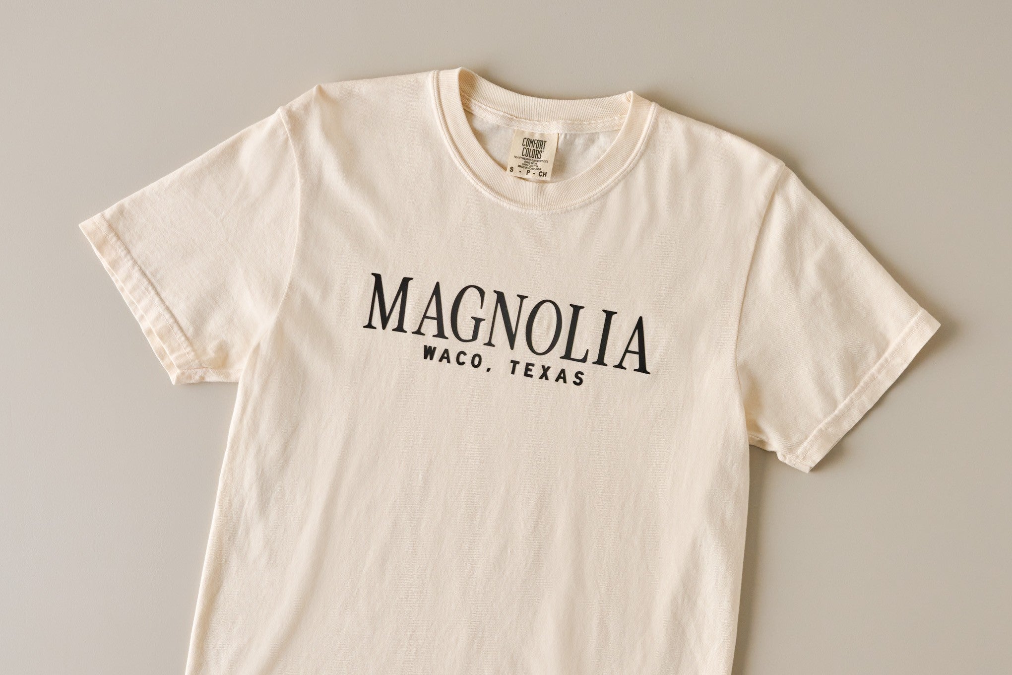 Shop t-shirts. Image features short sleeve ivory tee with Magnoliass on front.