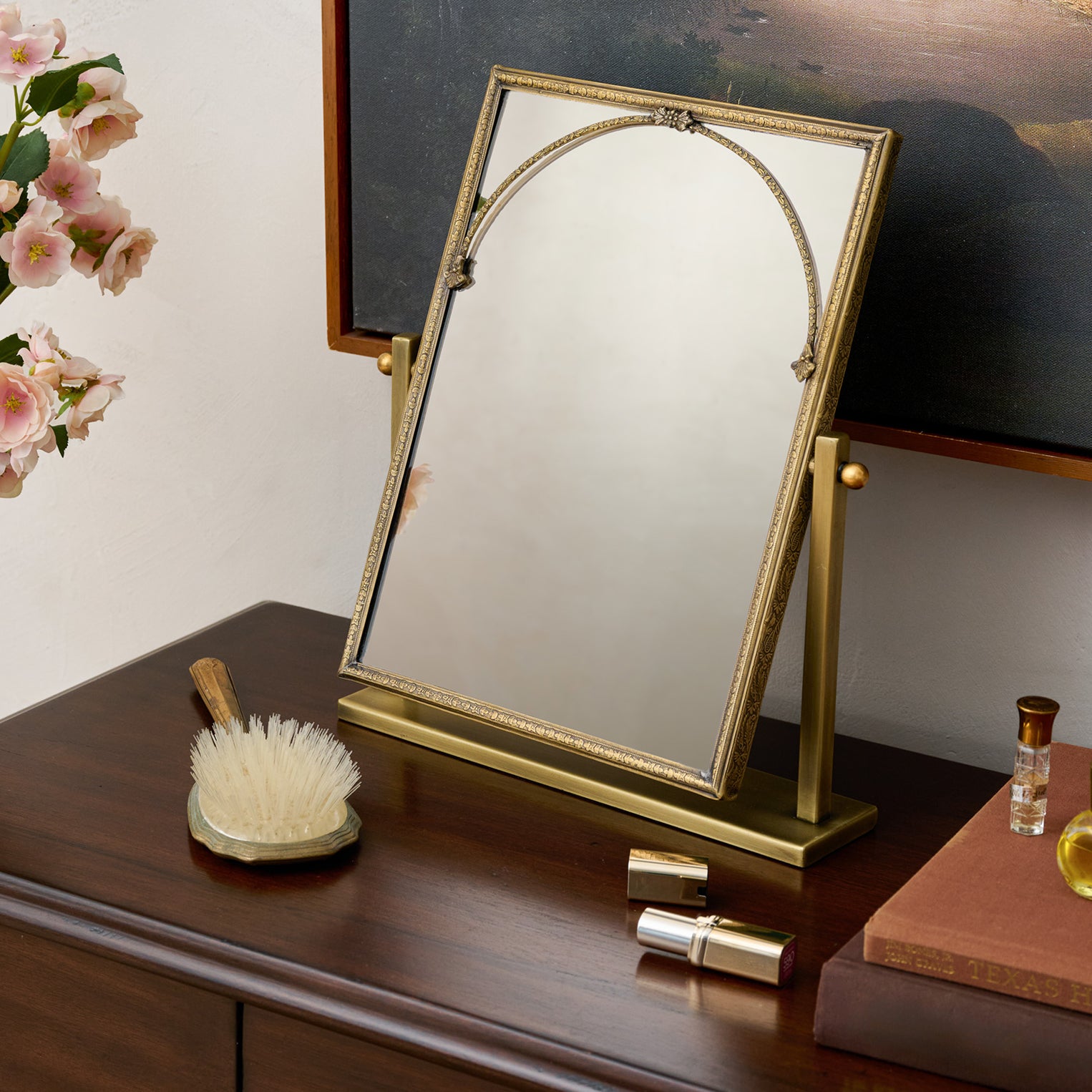 Gold-framed mirror on a wooden surface with decorative items.