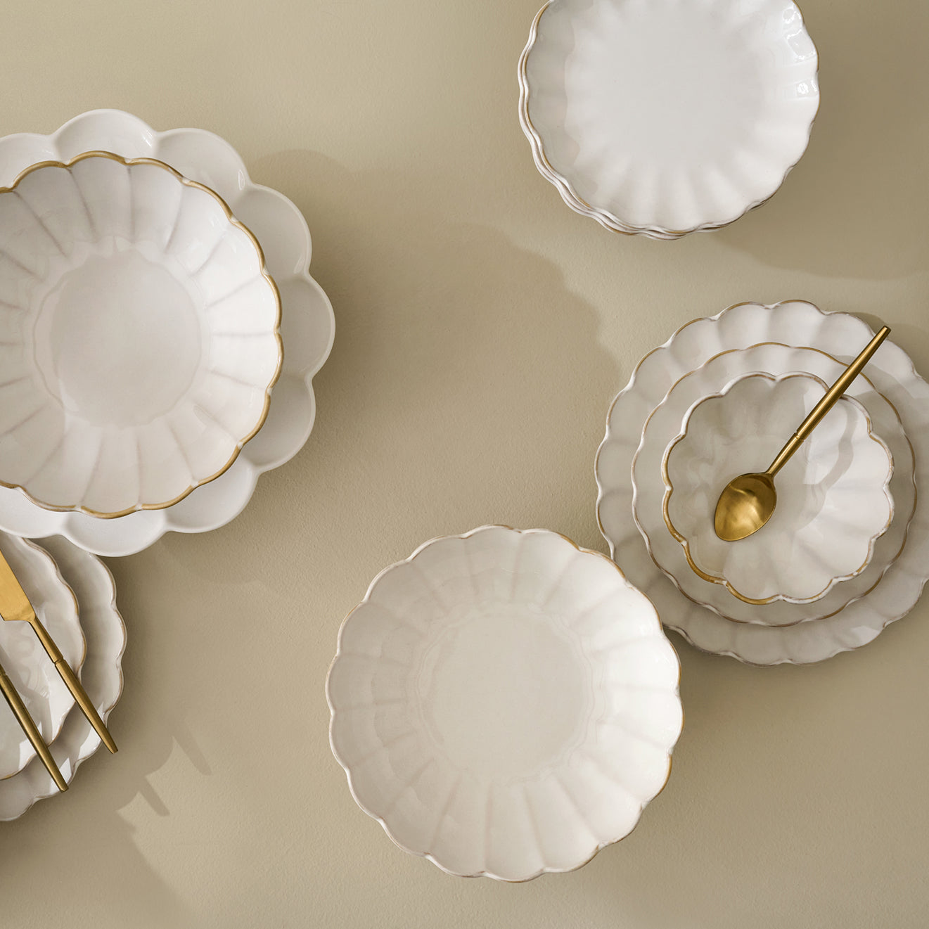 Set of white ceramic plates with gold accents on a beige background