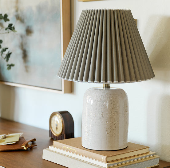 Table lamp with pleated shade on a stack of books in a home setting