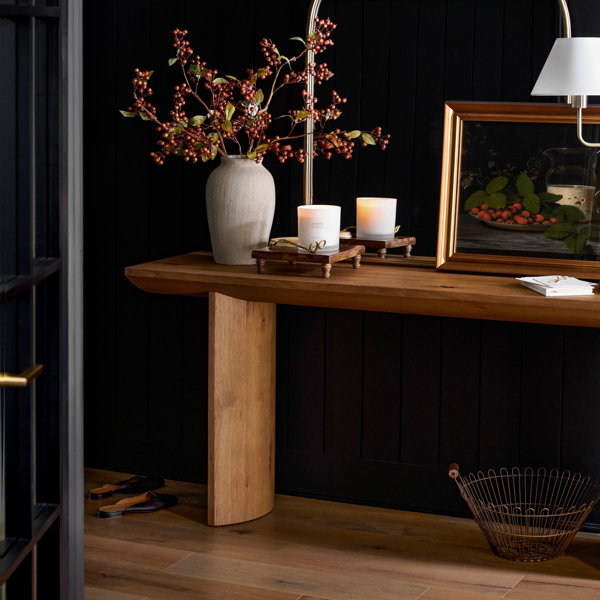 Suri Console Table against a black wall with a painting on top 