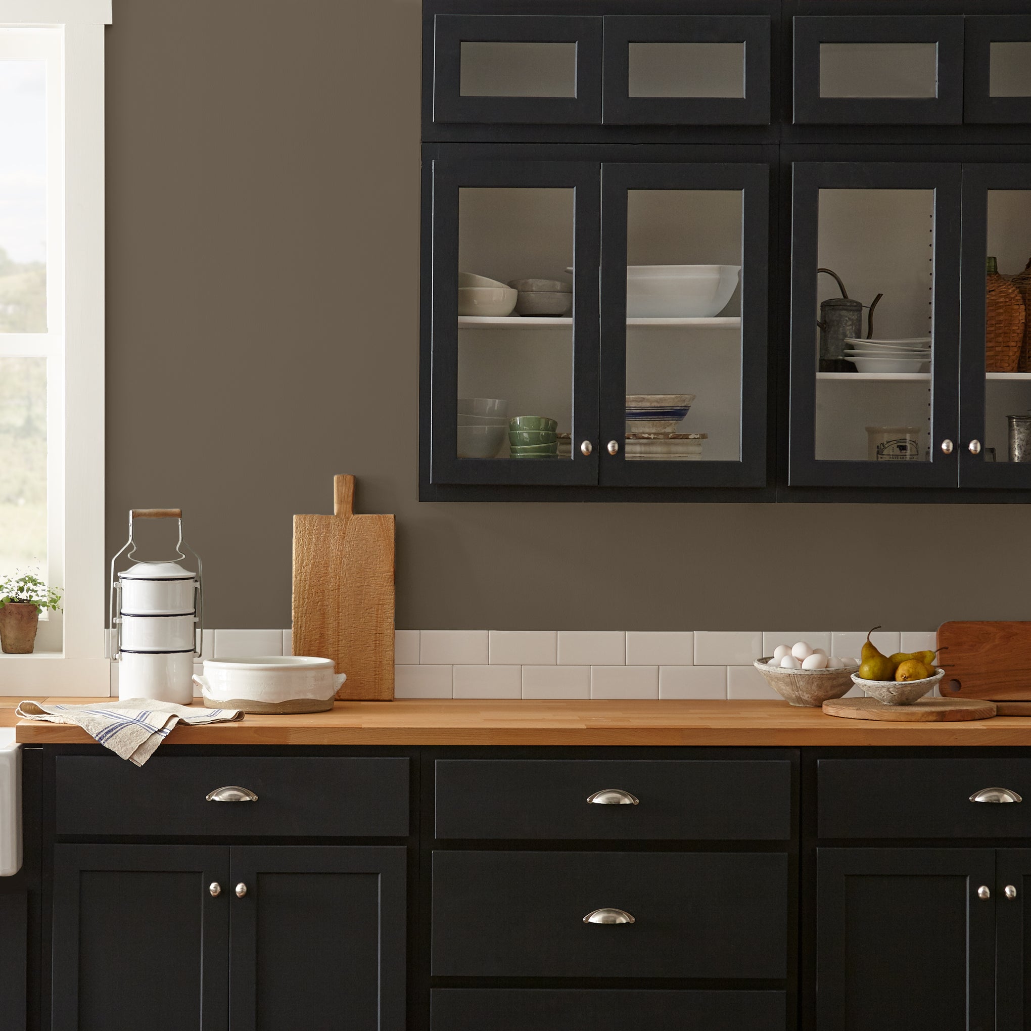 Mosswood paint featured in kitchen walls with dark blue cabinets and wood countertops