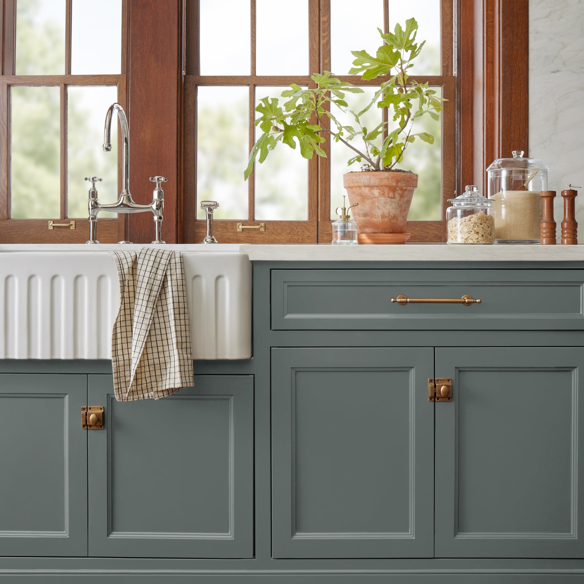 Ridge Rock paint featured on bottom kitchen cabinetry with white farmhouse sink, potted plant and glass kitchen jars