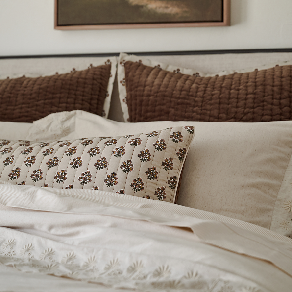 Close-up of a bed with textured pillows and embroidered bedding.  Shop the Bedroom.