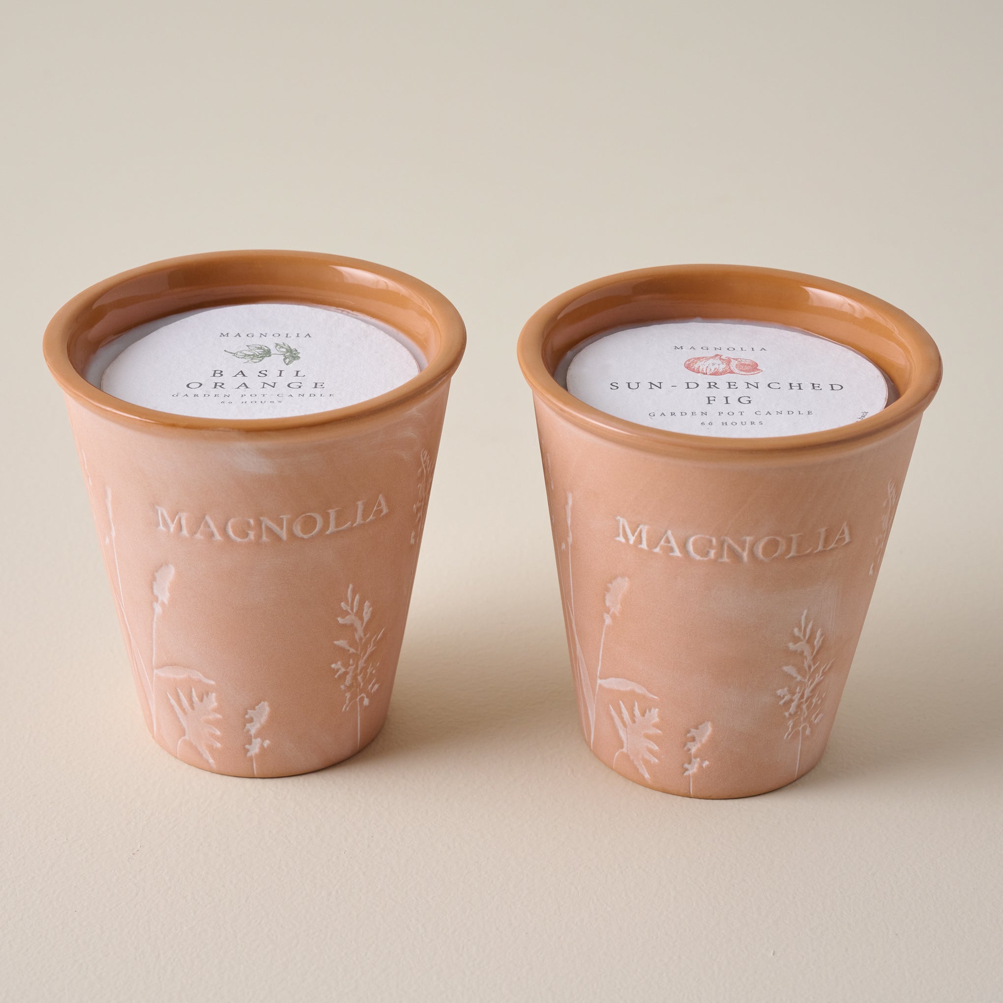 Magnoliass Sun-Drenched Fig Garden Pot Candle shown with Basil Orange candle