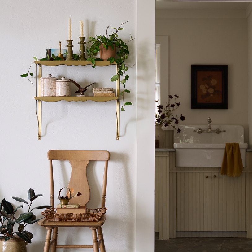 Nestled corner of a room with a wooden chair, decorative shelf, and sink. Shop Wall Decor and Mirrors.