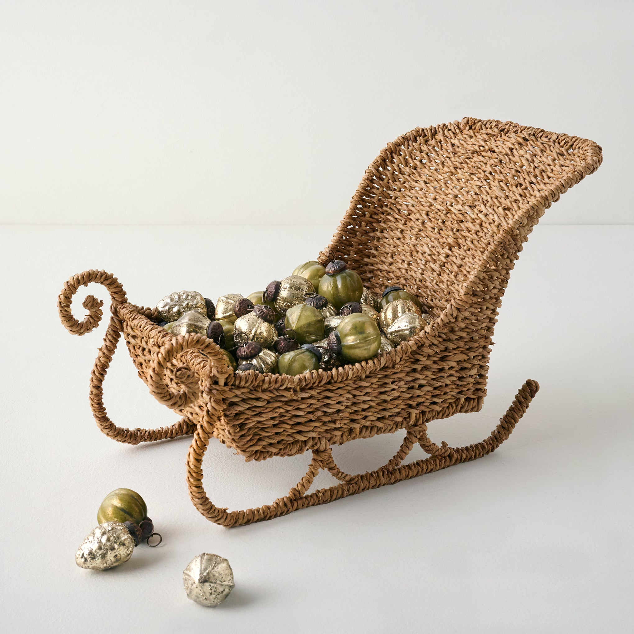 Green Antique Inspired Ornament Bowl Filler shown in woven sleigh
