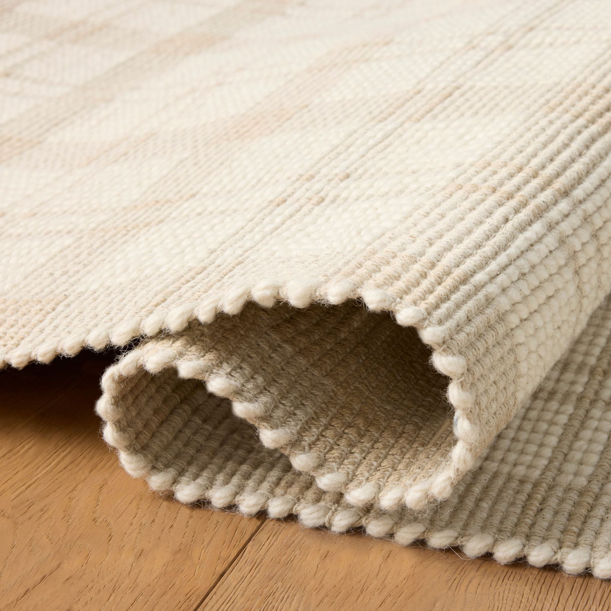 Ryder Beige Ivory Rug shown rolled/folded