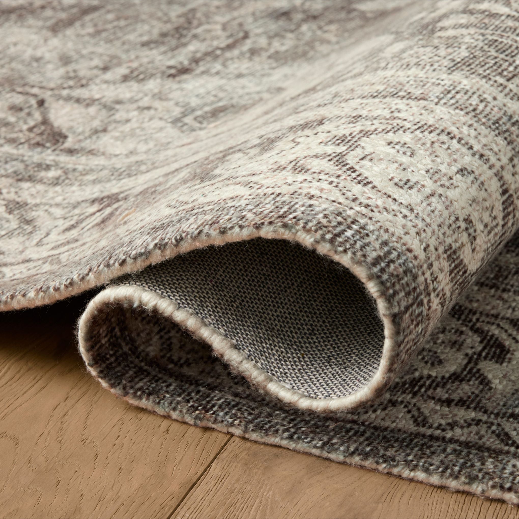 Wimberly Ink Bone Rug shown rolled/folded