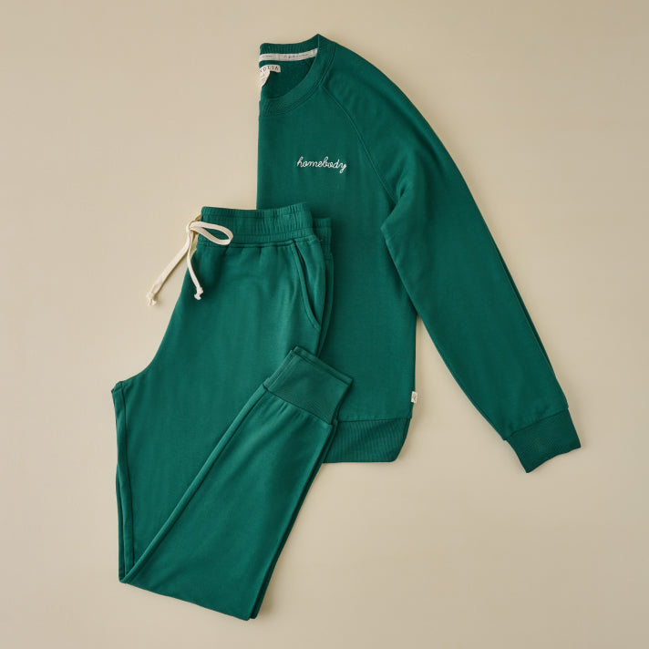 Green tracksuit with 'homebody' text on a beige background