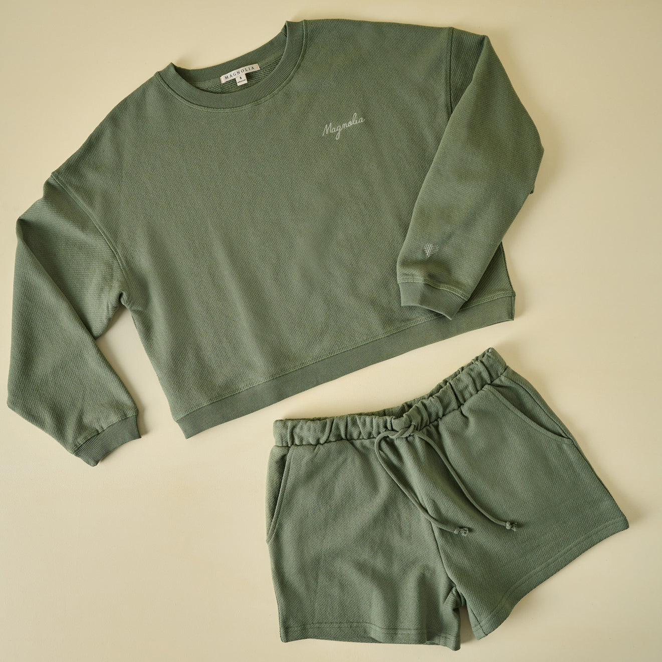 Green sweatshirt and shorts set on a beige background