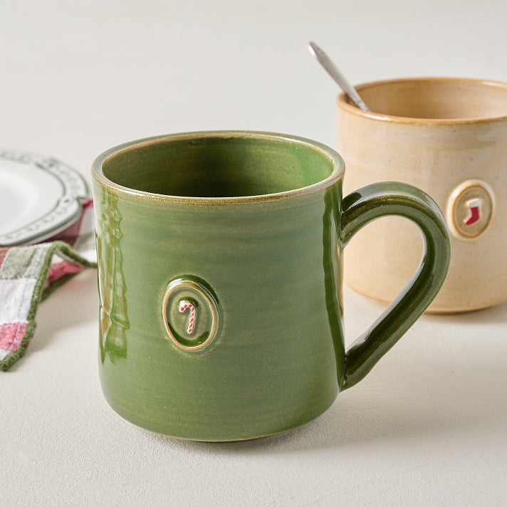 Green ceramic mug with decorative elements on a light surface