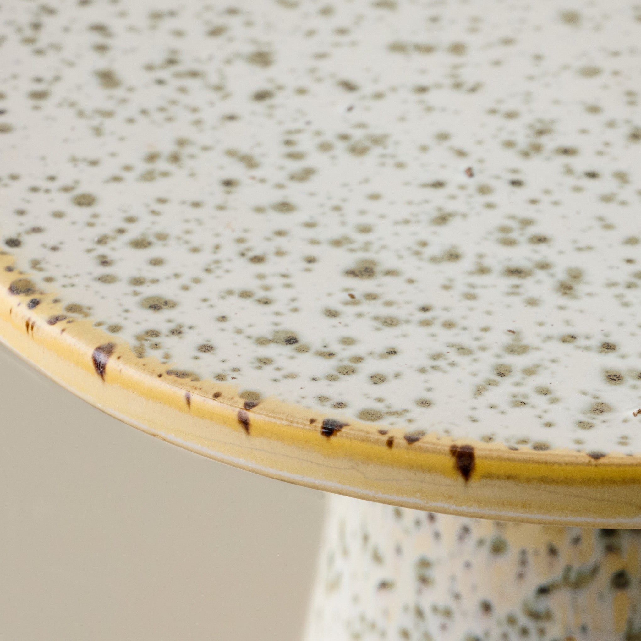 Close-up of a ceramic cake stand with speckled green glaze