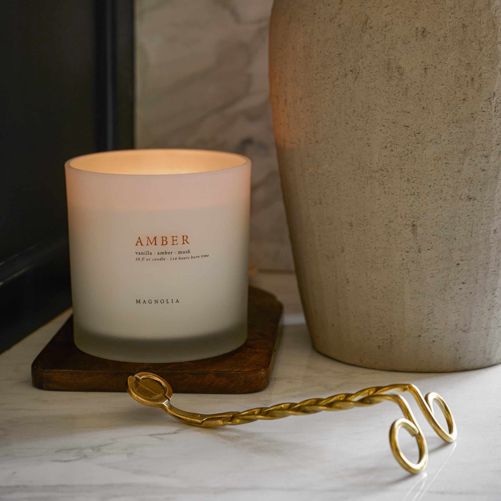 Magnoliass Amber Candle next to a large vase