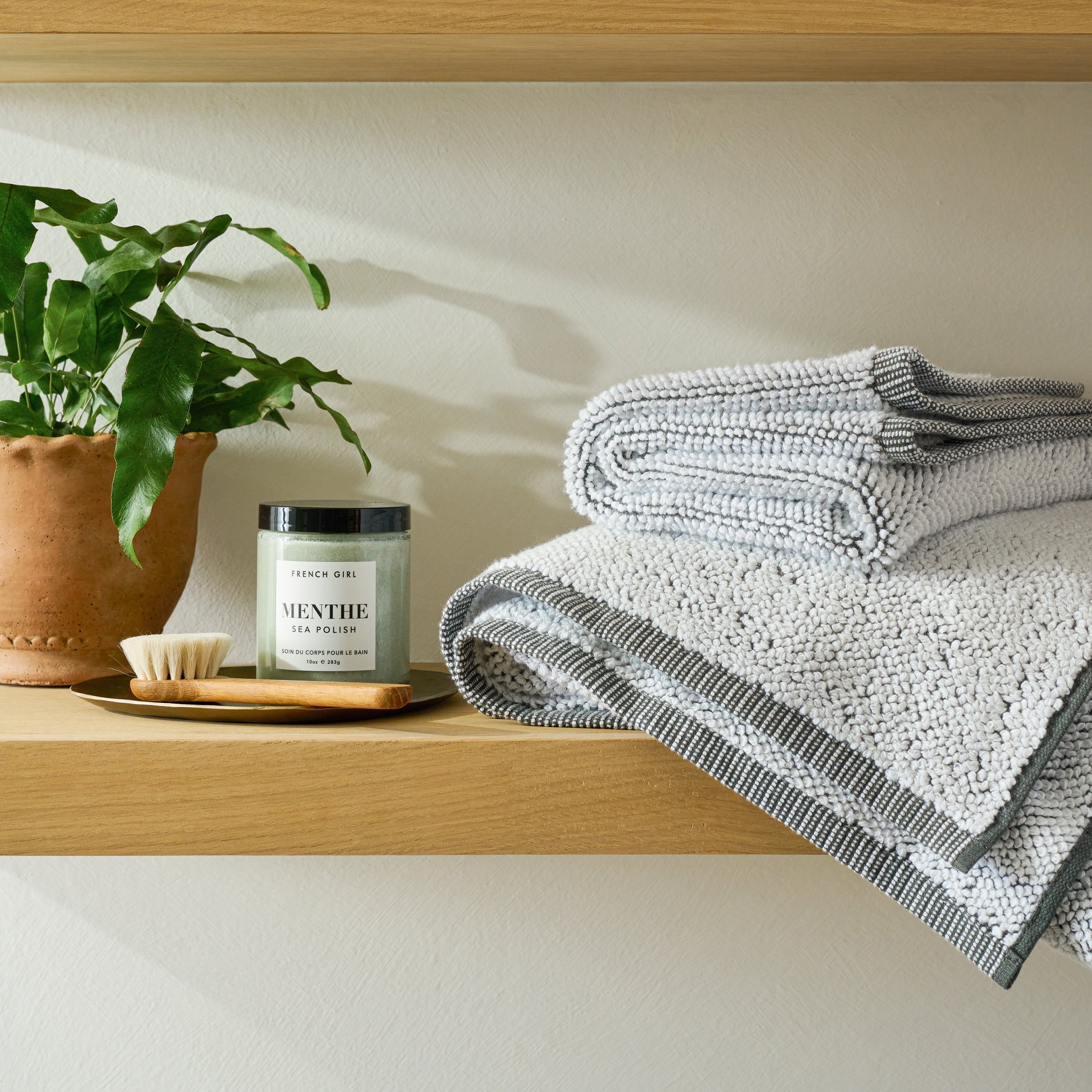 Charcoal Assisi Textured Towel on a shelf in a bathroom 
