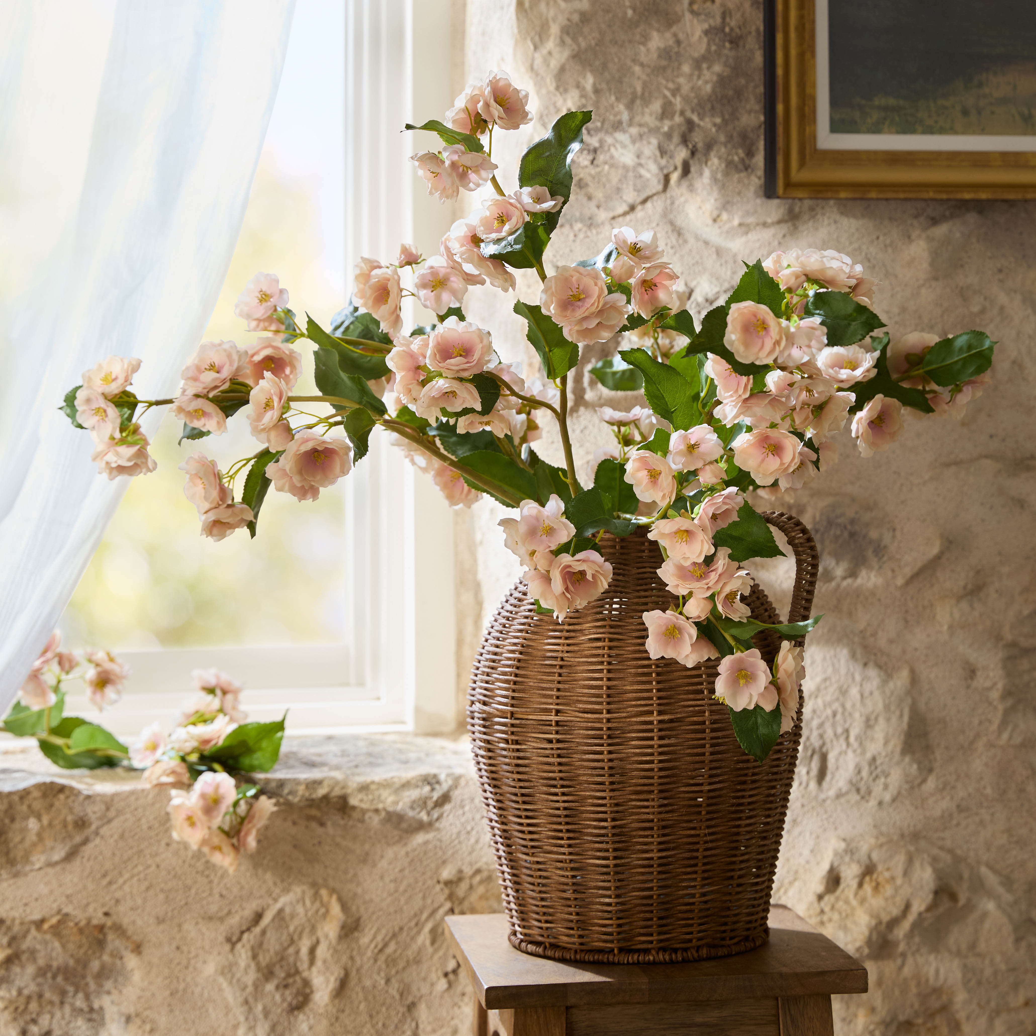 Blake Woven Rattan Jug Vase paired with peach flowers on top of end table