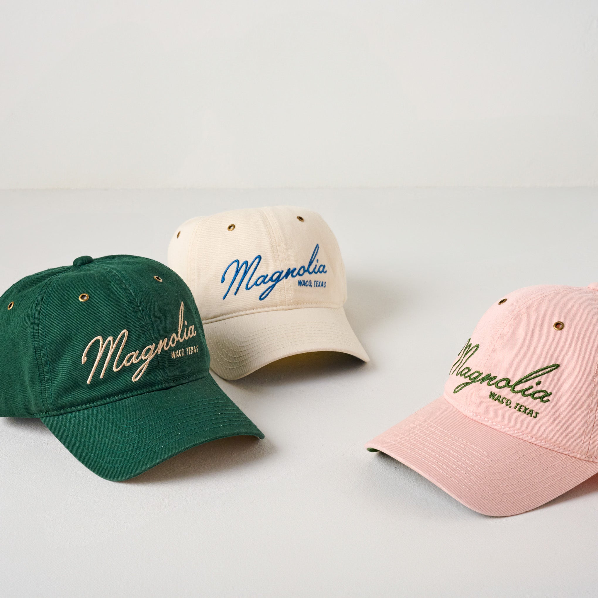 Magnoliass Embroidered Script Hunter Green Hat shown with pink and cream hats