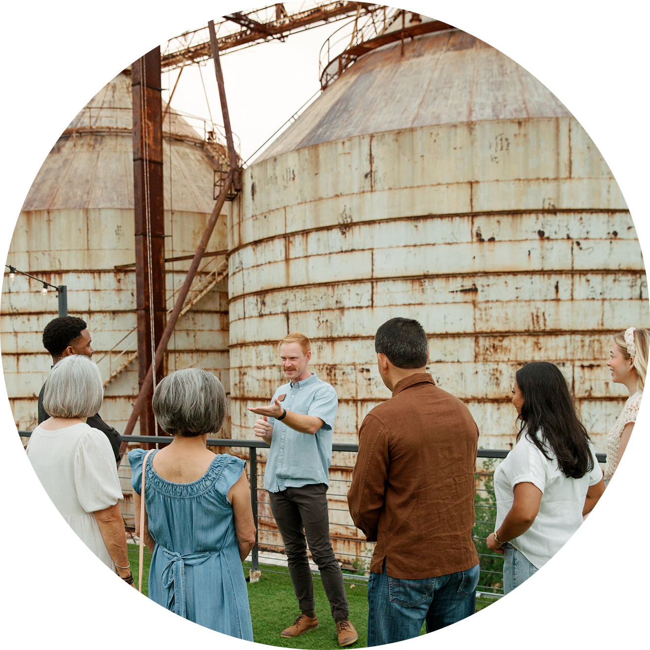 Group of people standing in front of rusted silos for the Chip and Joanna, Story of Magnoliass Tour.