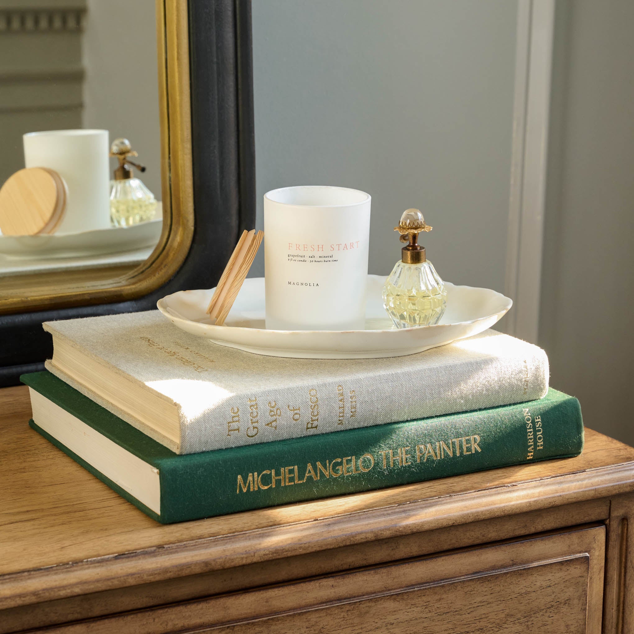 Magnoliass Fresh Start Candle shown on stack of books on tray