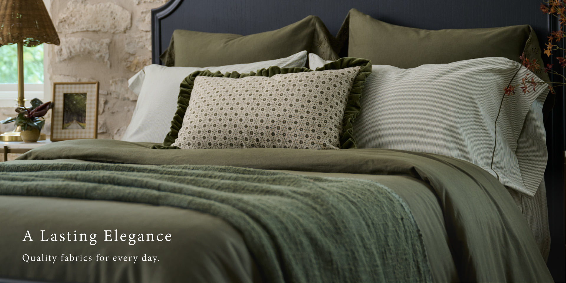 Bed with green bedding and decorative pillows in a cozy bedroom setting.  Shop Bedding.