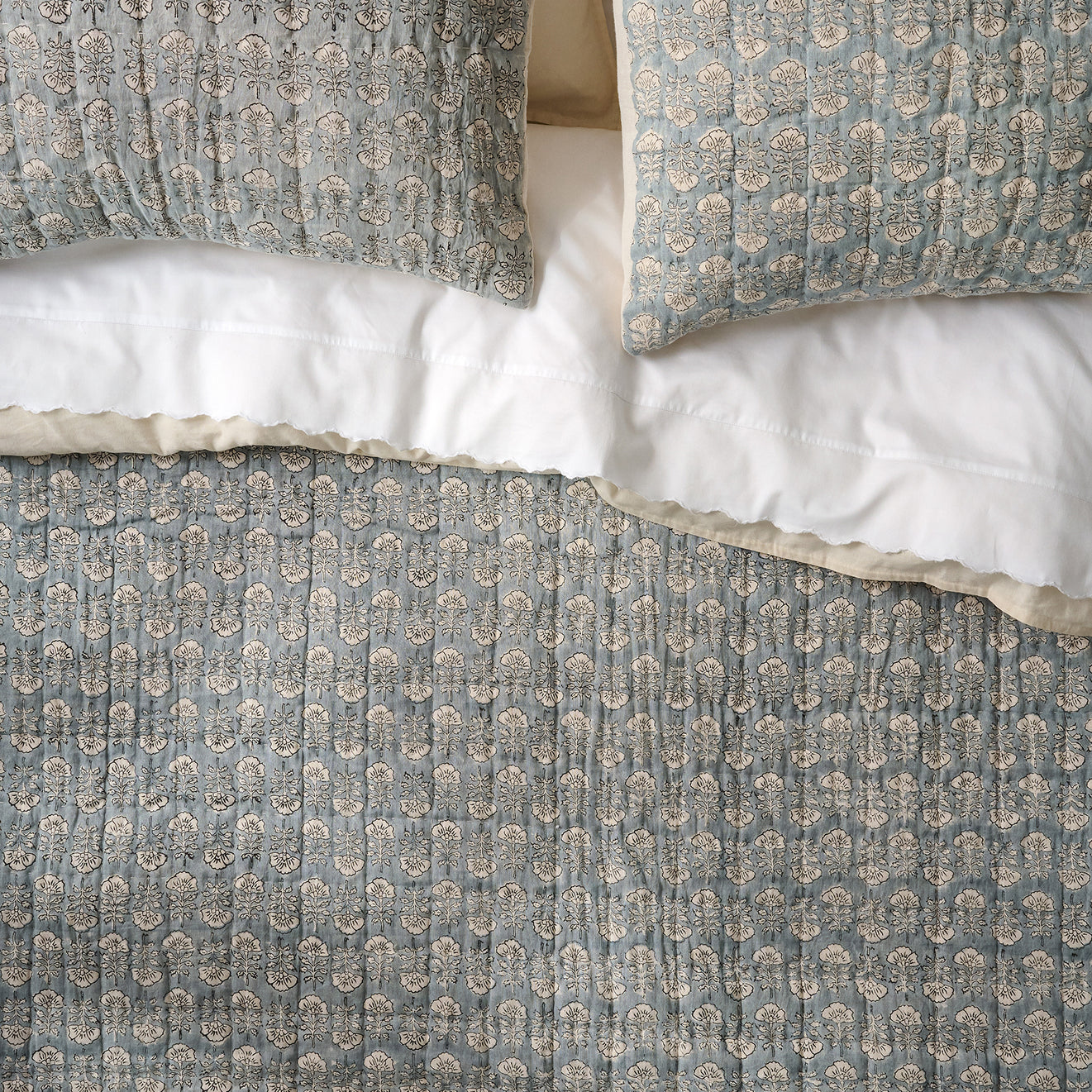 Flora Blue patterned pillows and duvet cover on a bed.