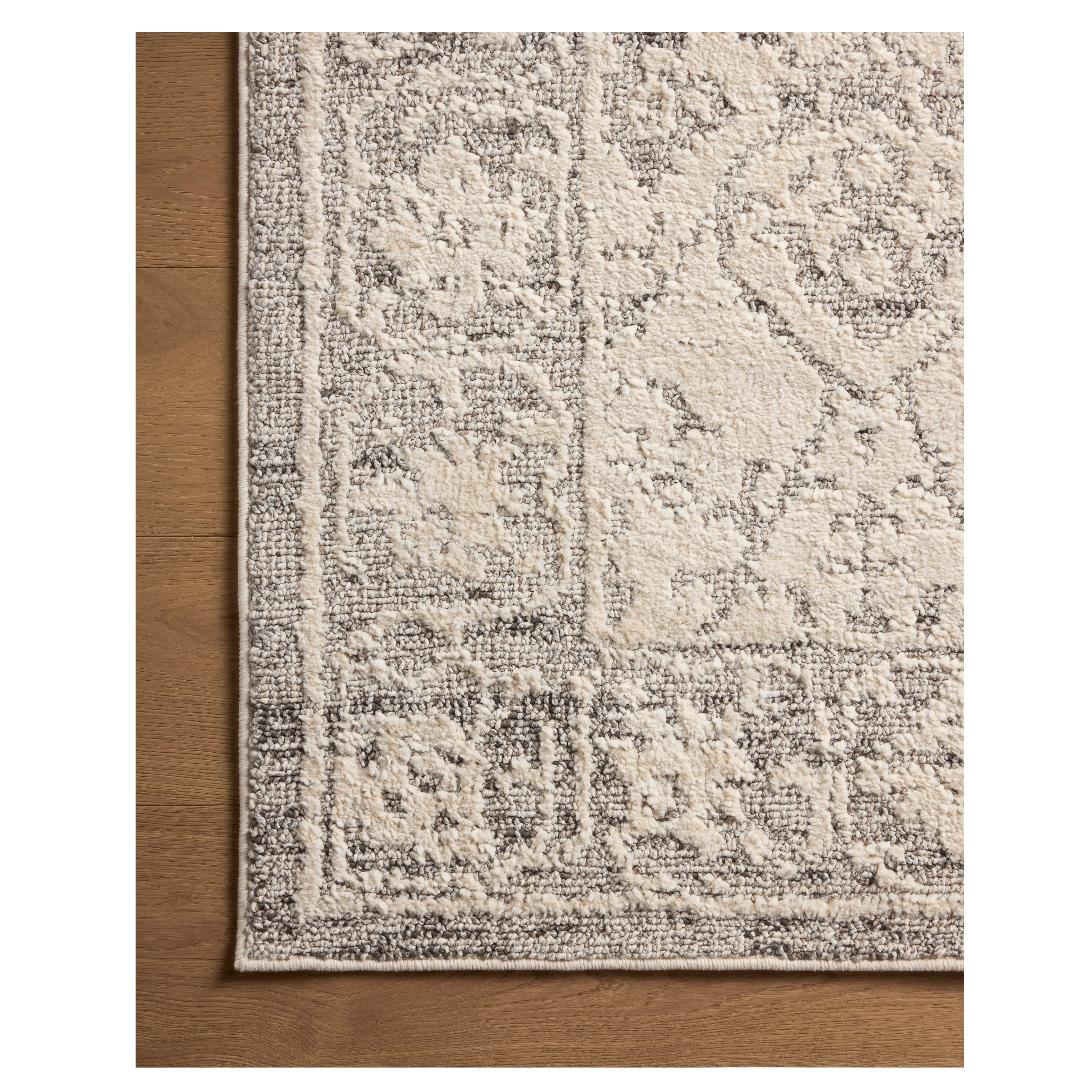 Gigi Ivory Stone Rug close up of corner of rug on wood floor