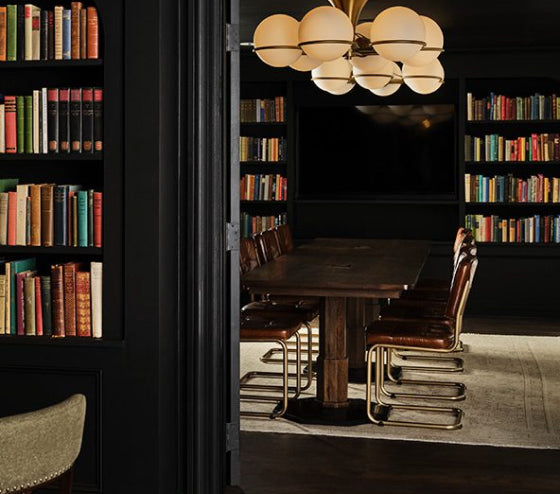 Library at Hotel 1928 with a wooden table and chairs in a room filled with bookshelves.