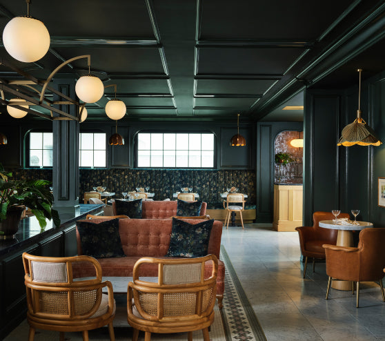 Bertie's on the Rooftop at Hotel 1928, a modern restaurant interior with dark walls, wooden chairs, and pendant lights.