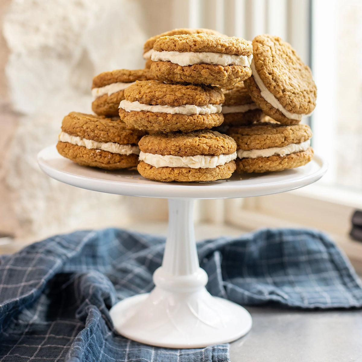 Stack of oatmeal cream pies on a white cake stand with a blurred background.