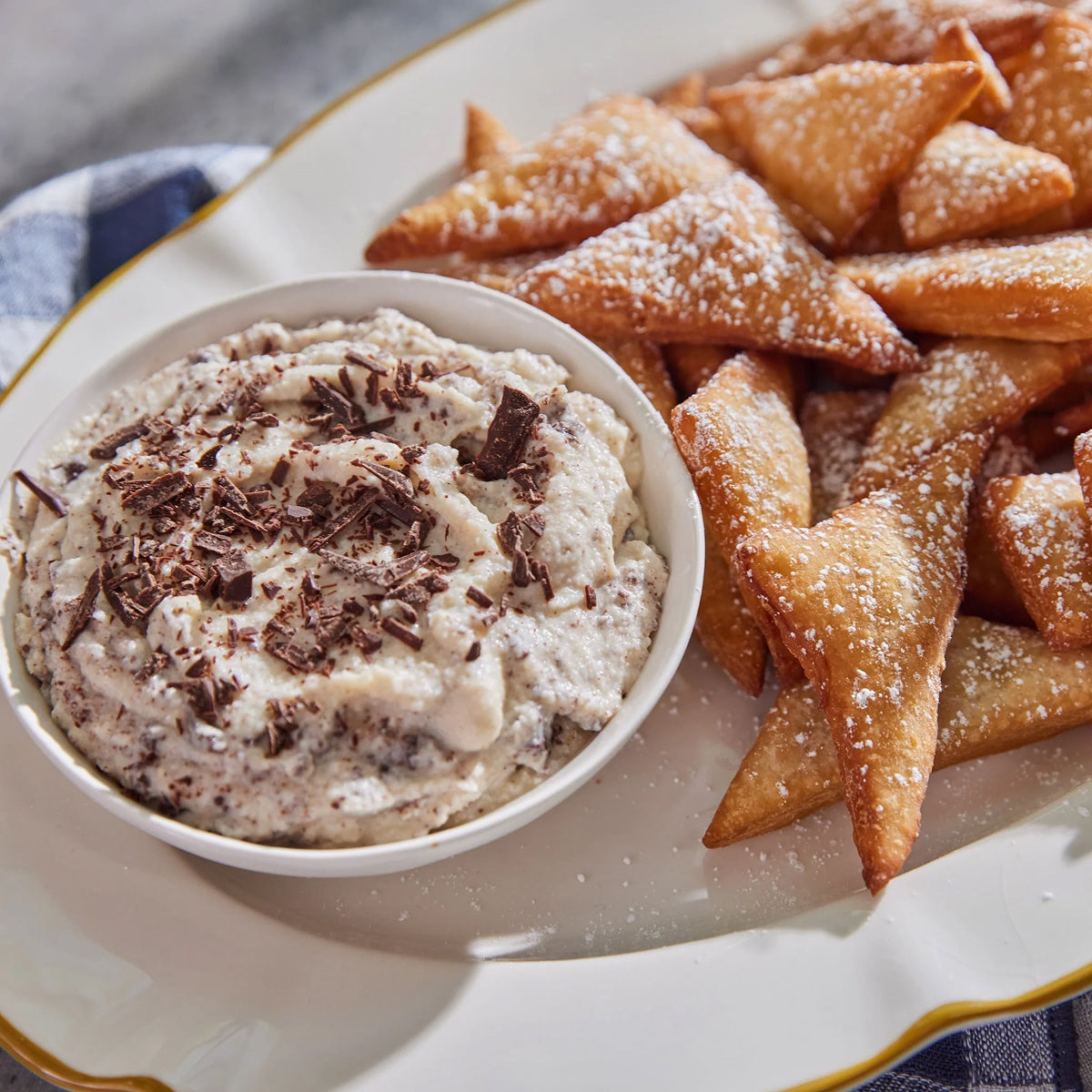 Dessert platter with cannoli cream and ladyfinger cookies on a white plate.
