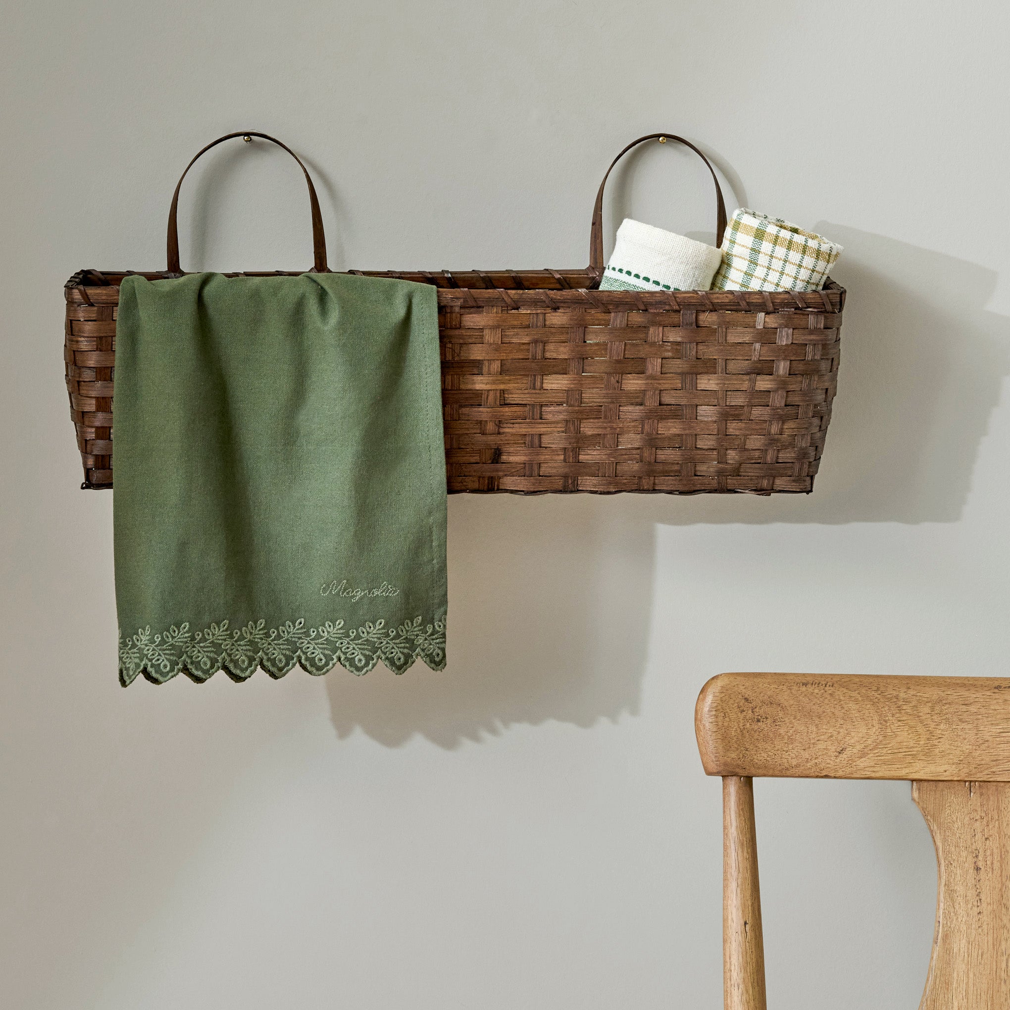 Magnoliass Embroidered Scalloped Edge Tea Towel shown in basket on wall
