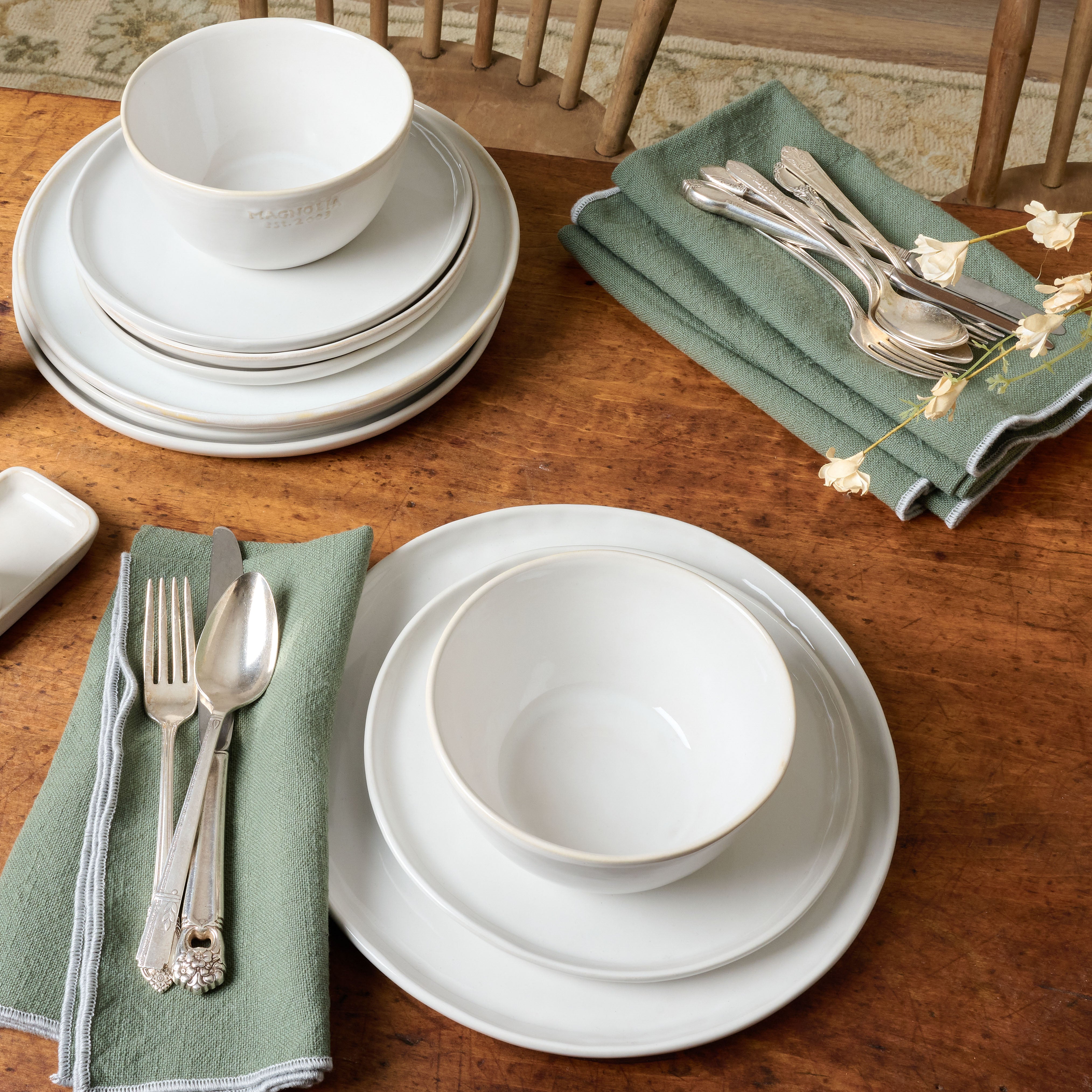 Magnoliass Est. Cereal Bowl with matching plates set on a rustic wood table with napkins and silverware