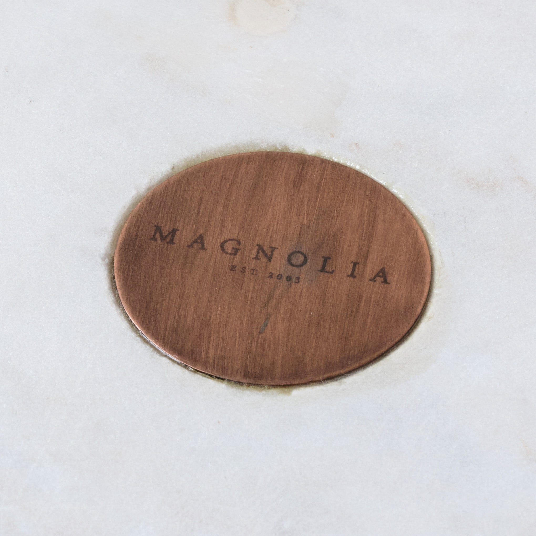 Marble and Copper Cake Stand close up of Magnoliass logo on center of marble