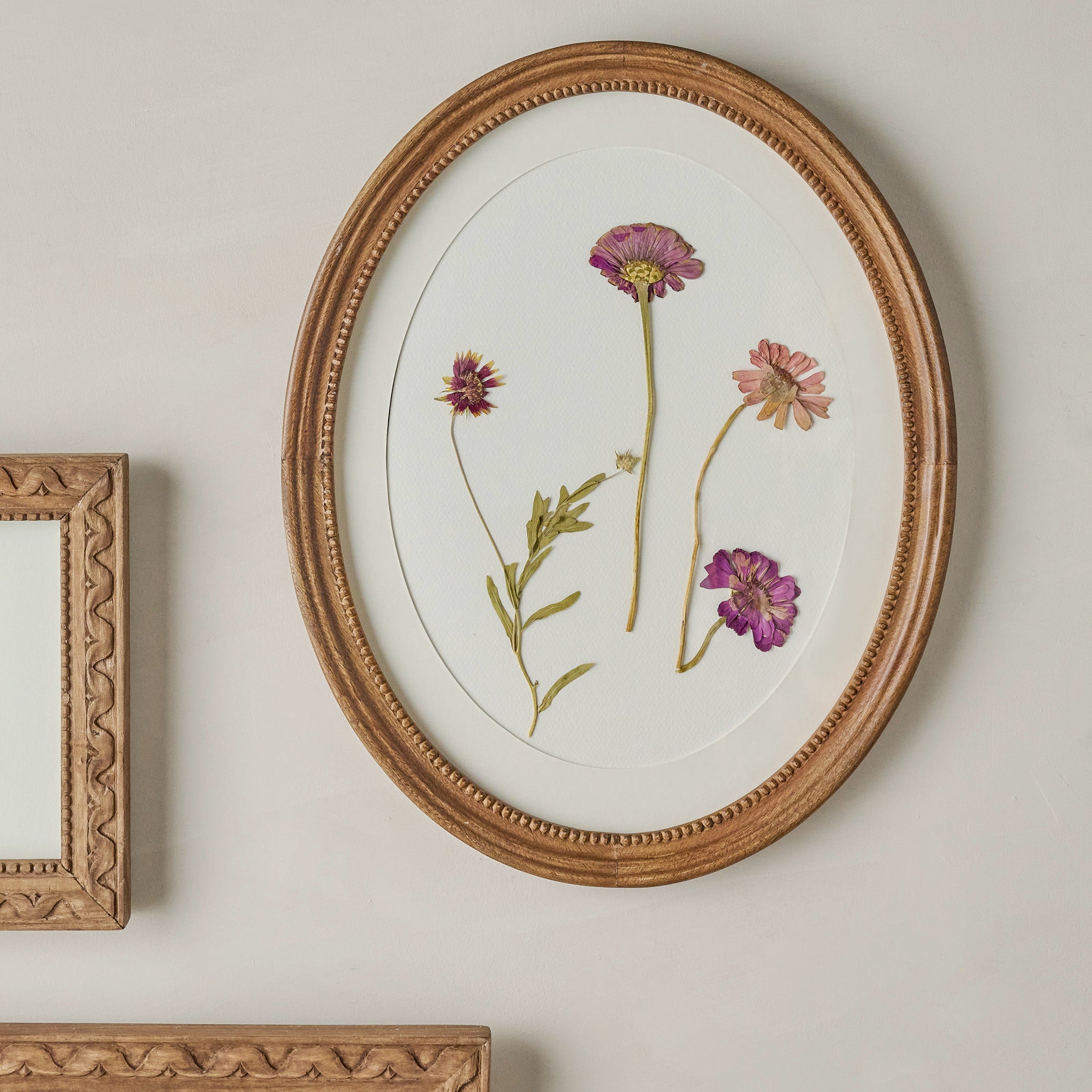 Willa Antiqued Wood Oval Picture Frame shown on wall
