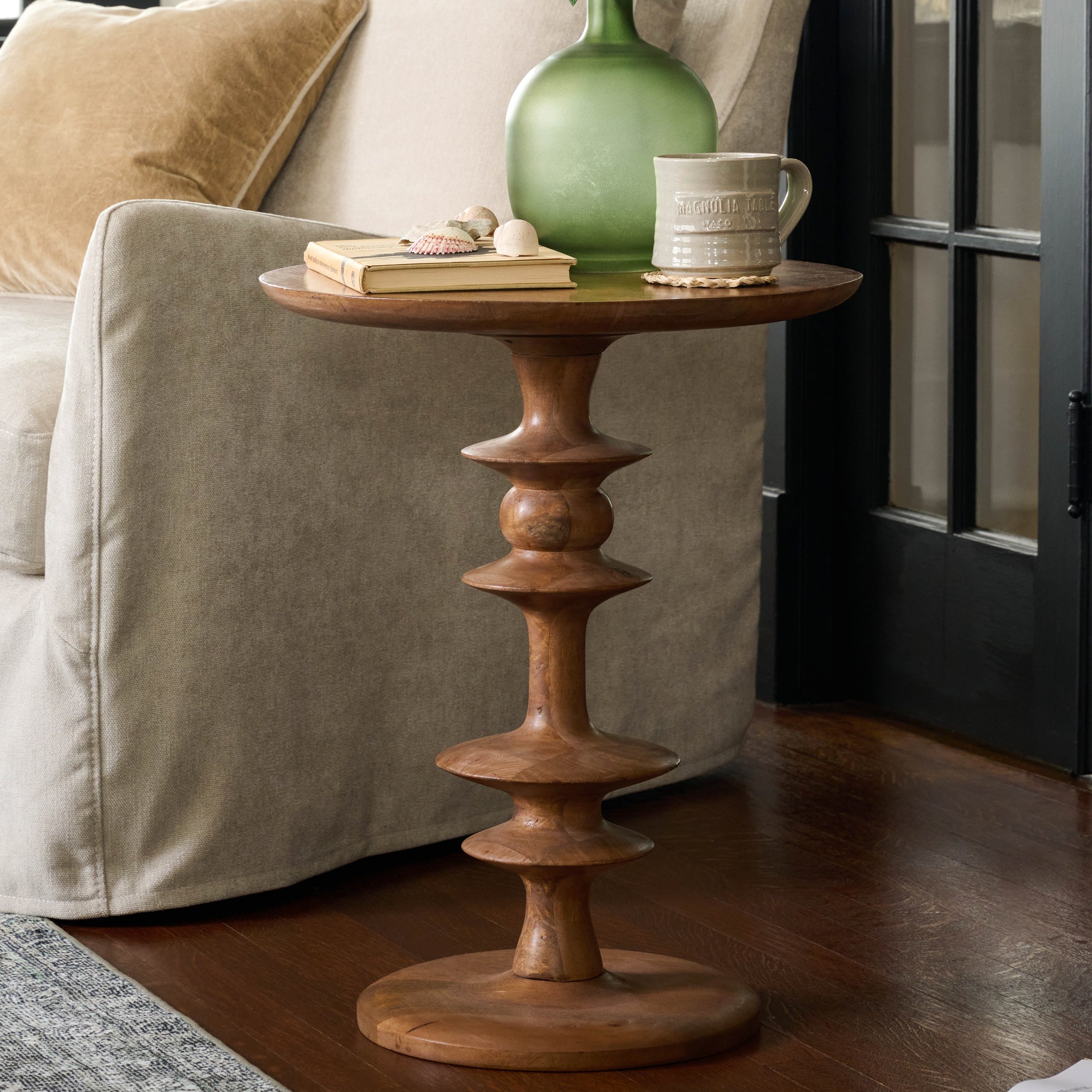 Enzo Turned Wood Side Table in color honey Mango shown next to a sofa