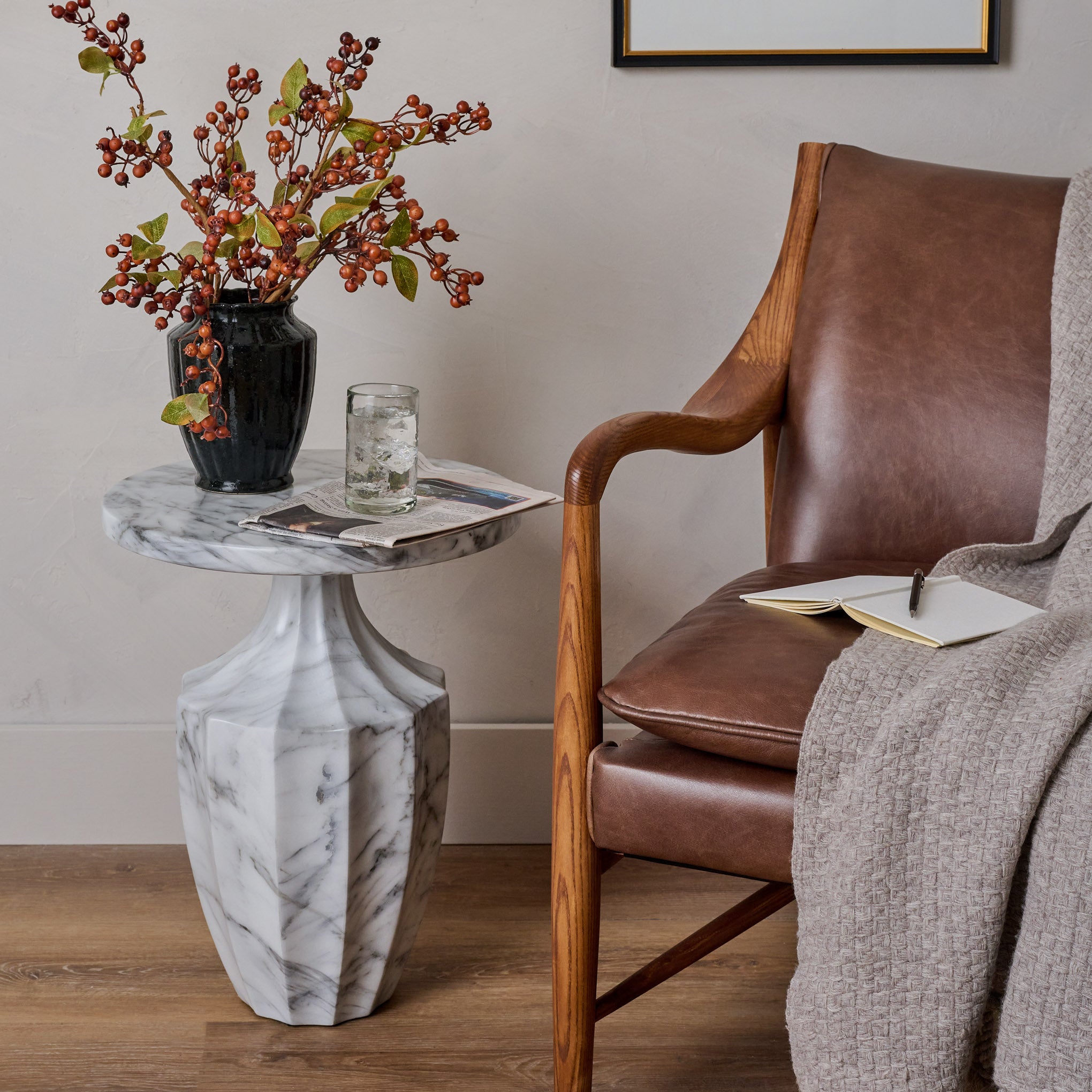 Fluted End Table shown holding vase of flowers and glass of water next to chair
