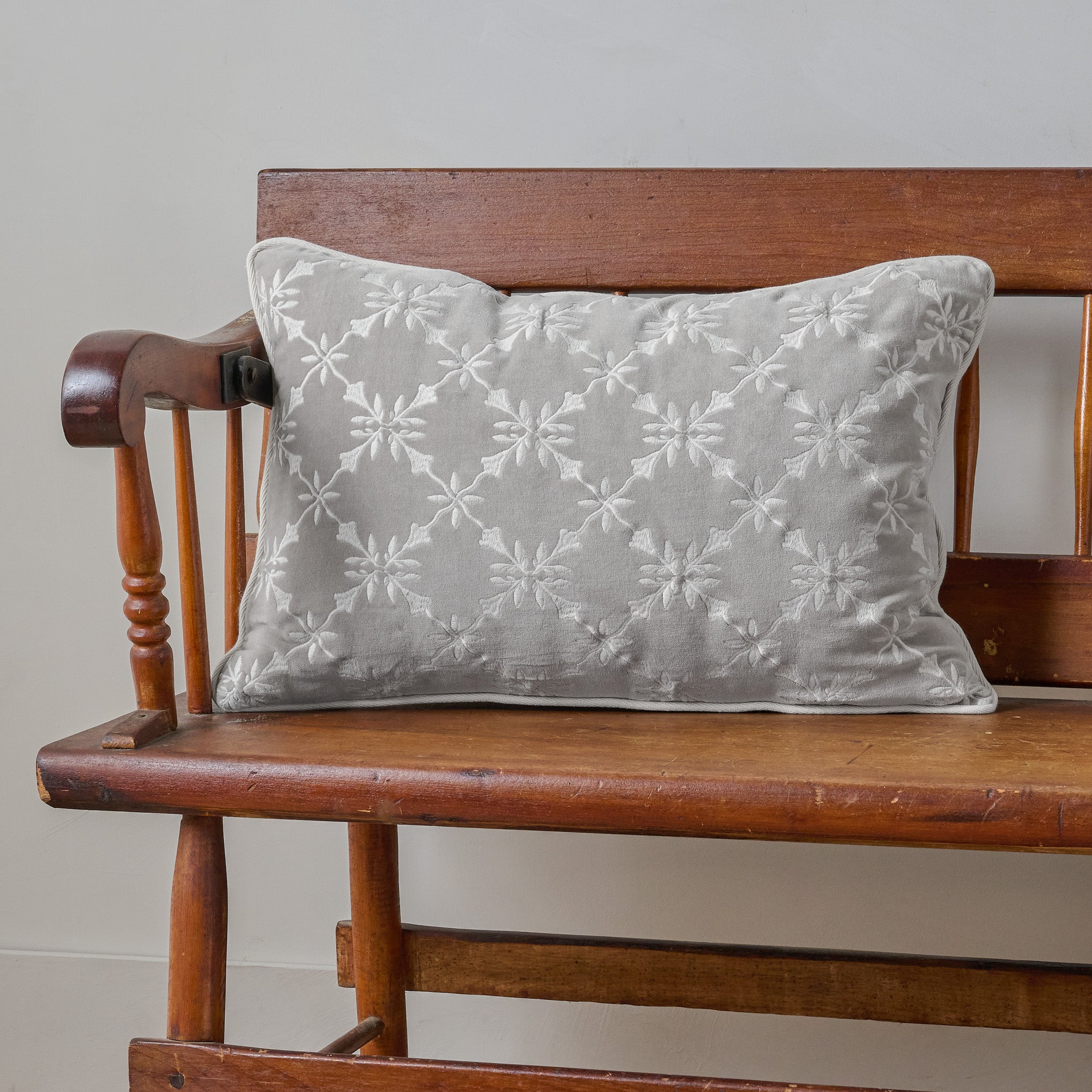 Aurora Embroidered Velvet Lumbar Pillow shown on bench