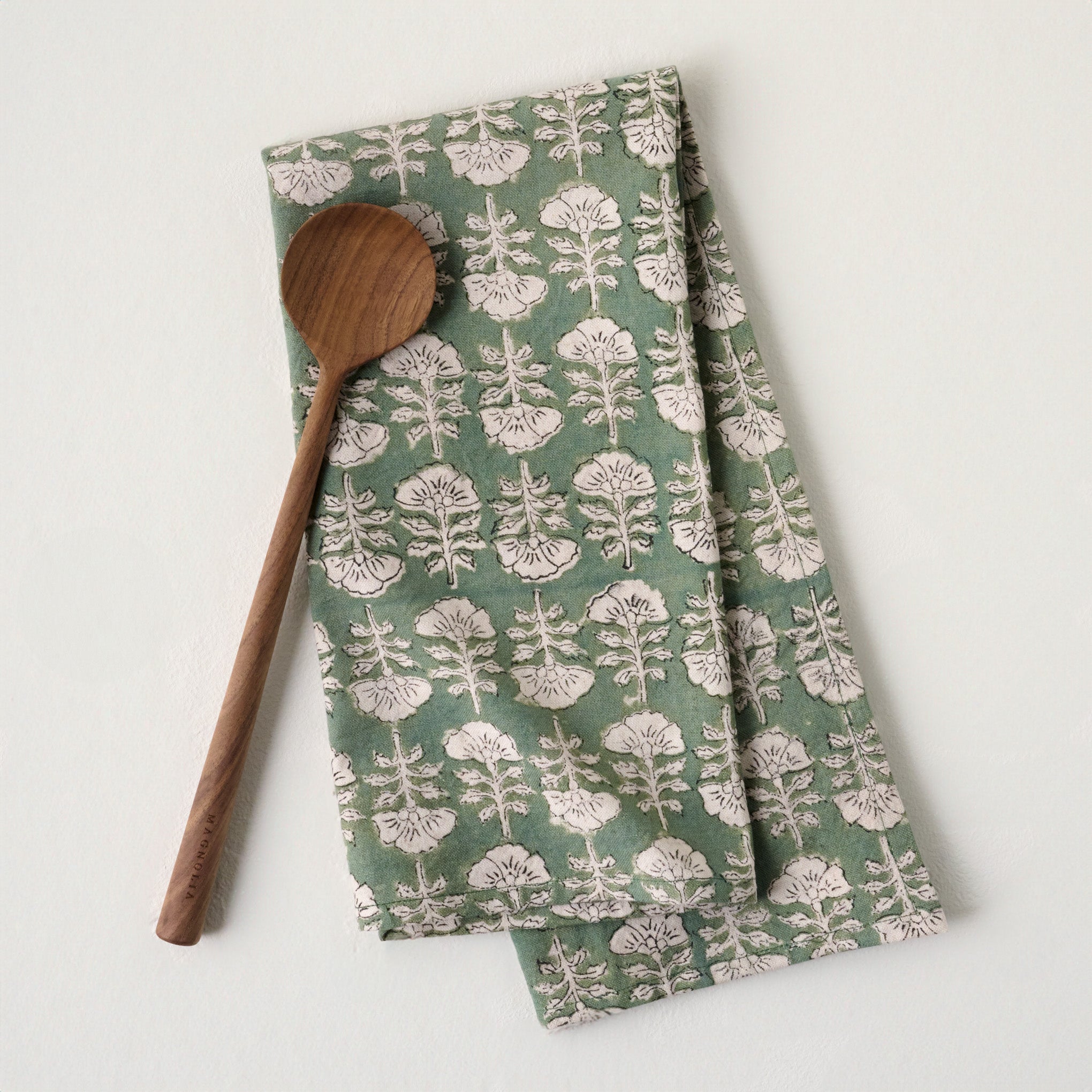 Flora Dusty Green Printed Tea Towel shown with wooden spoon