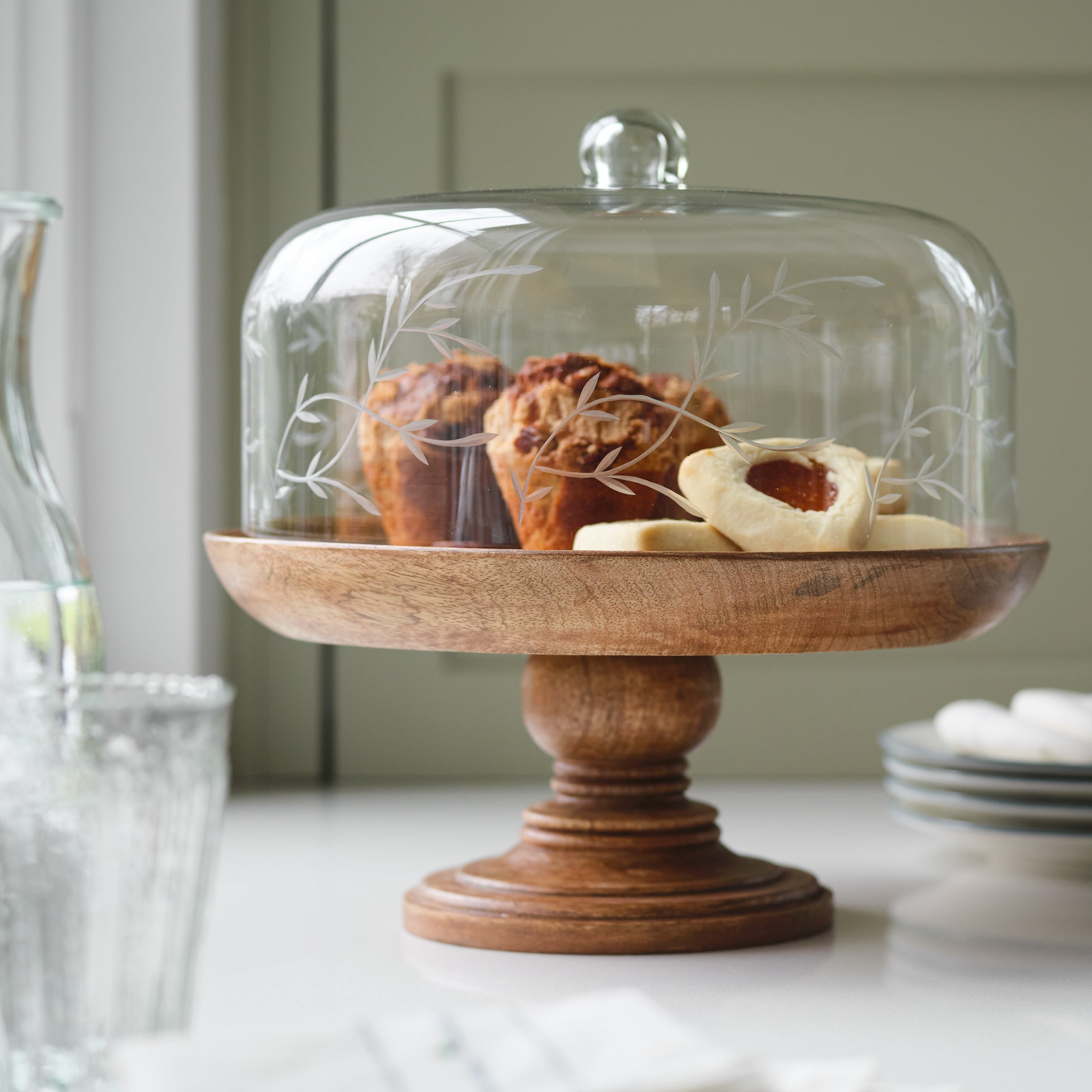 Eliane Etched Glass Cake Stand shown on kitchen counter with pastries