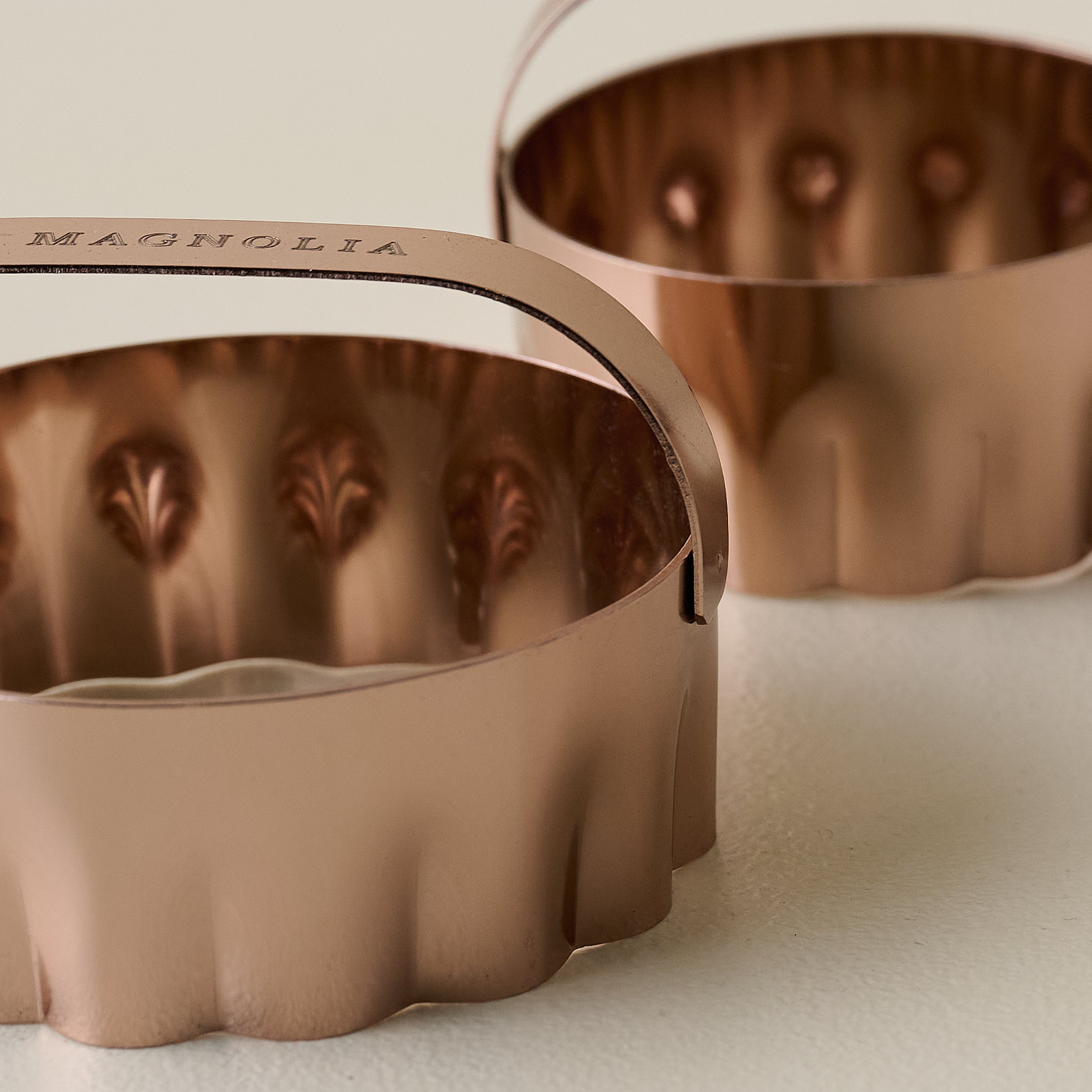 Close up view of two copper biscuit cutter with flat Magnoliass branded handles