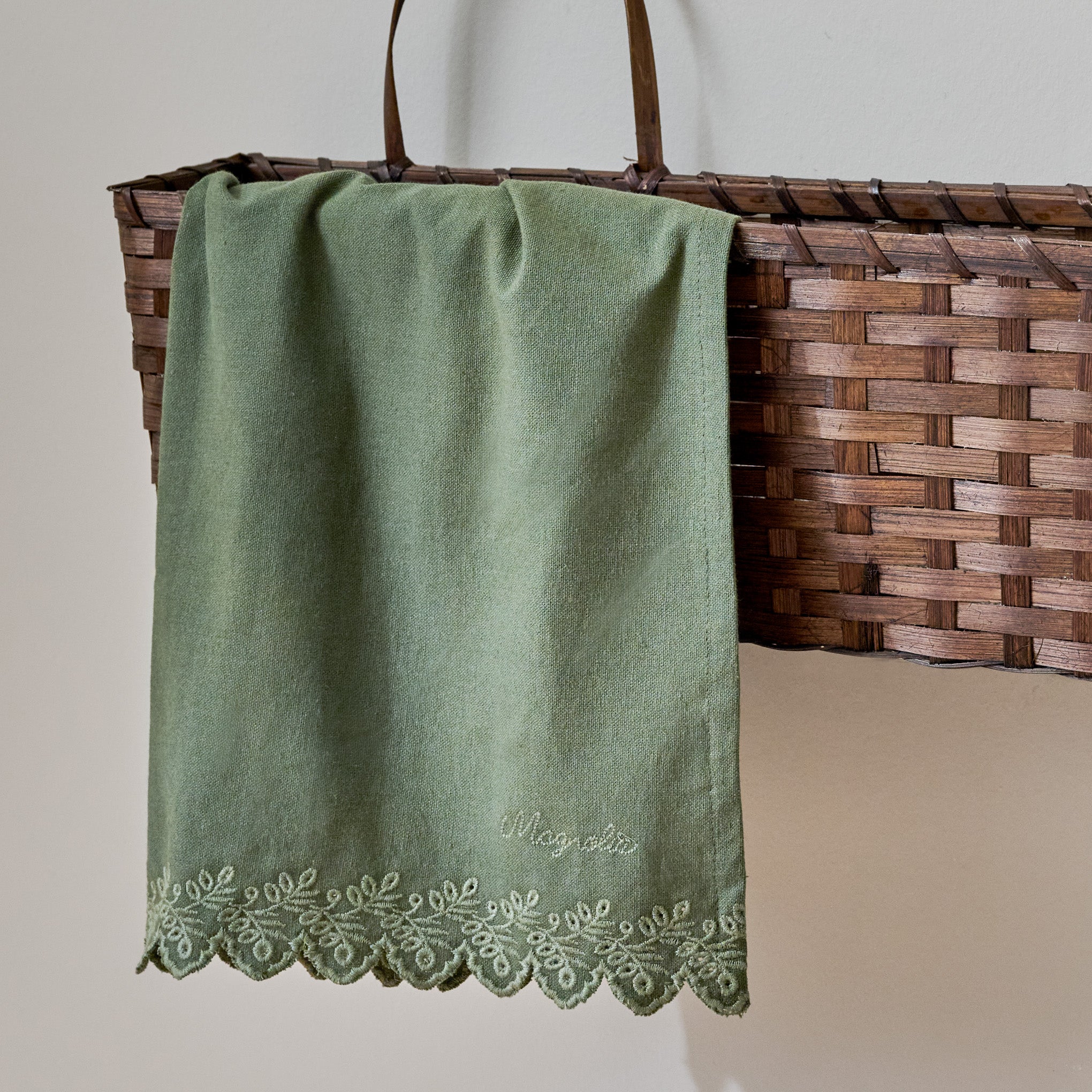 Magnoliass Embroidered Scalloped Edge Tea Towel shown in basket on wall