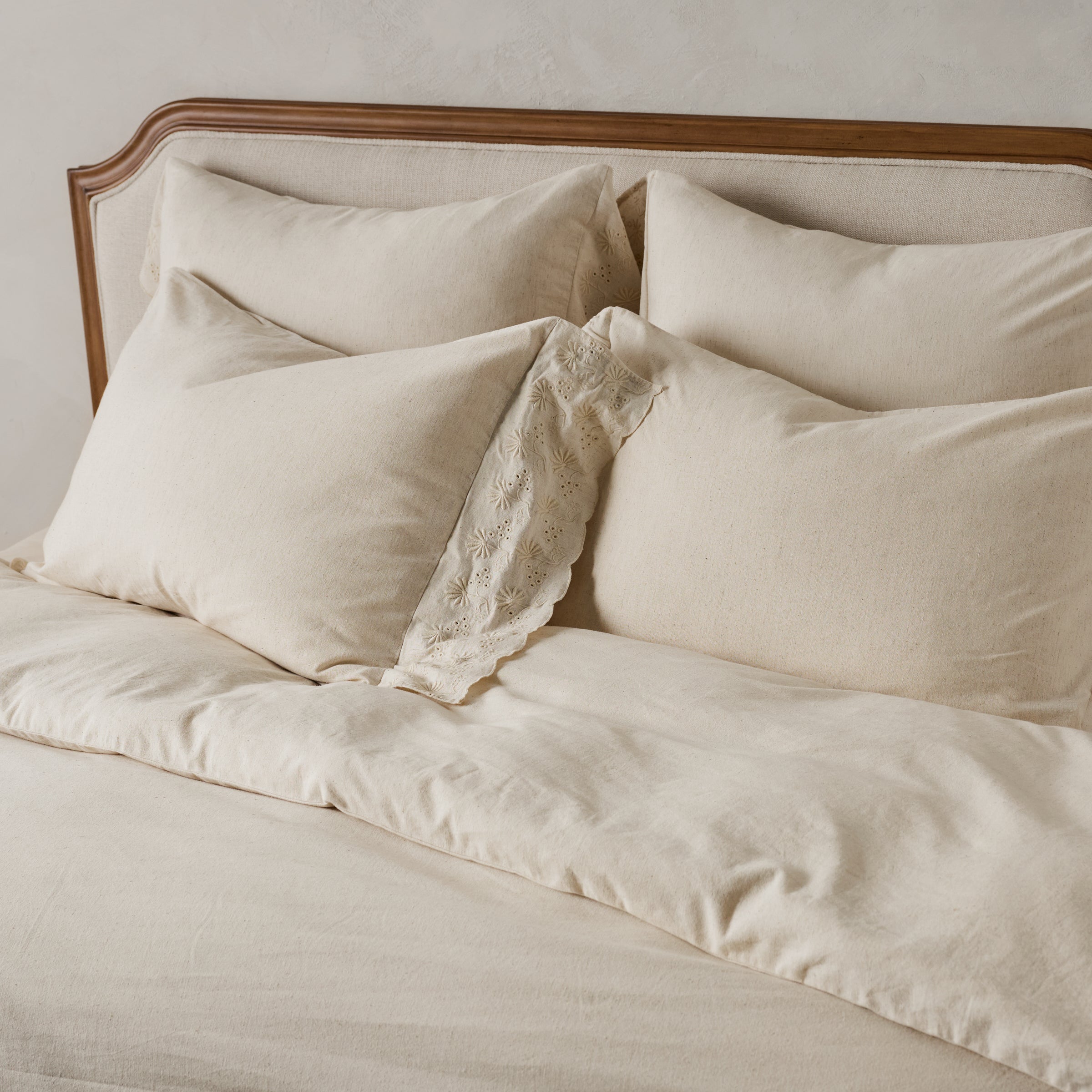 Clara Eyelet Flange Shams in Natural shown on bed