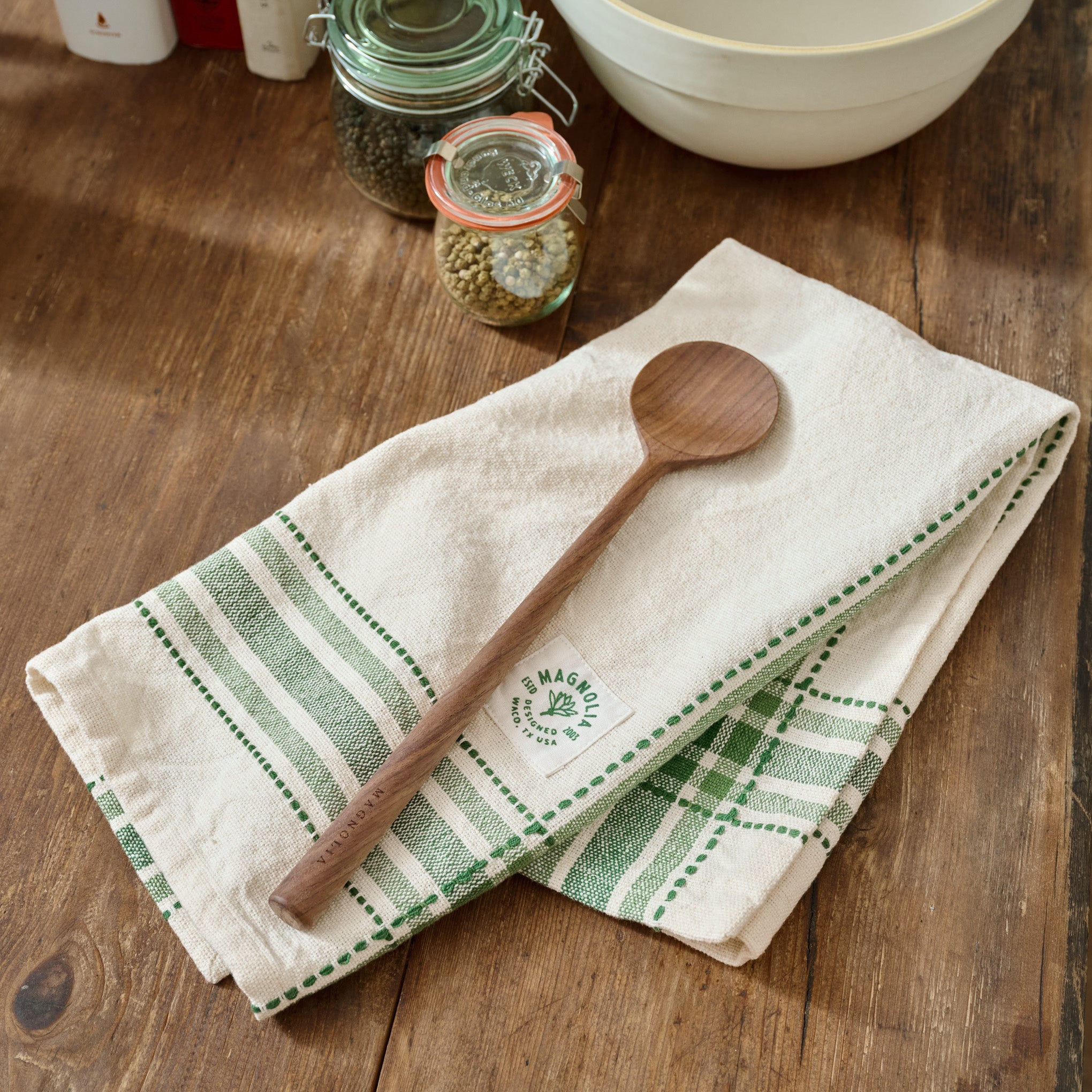 Magnoliass Vintage Green Border Tea Towel shown on table with wooden spoon