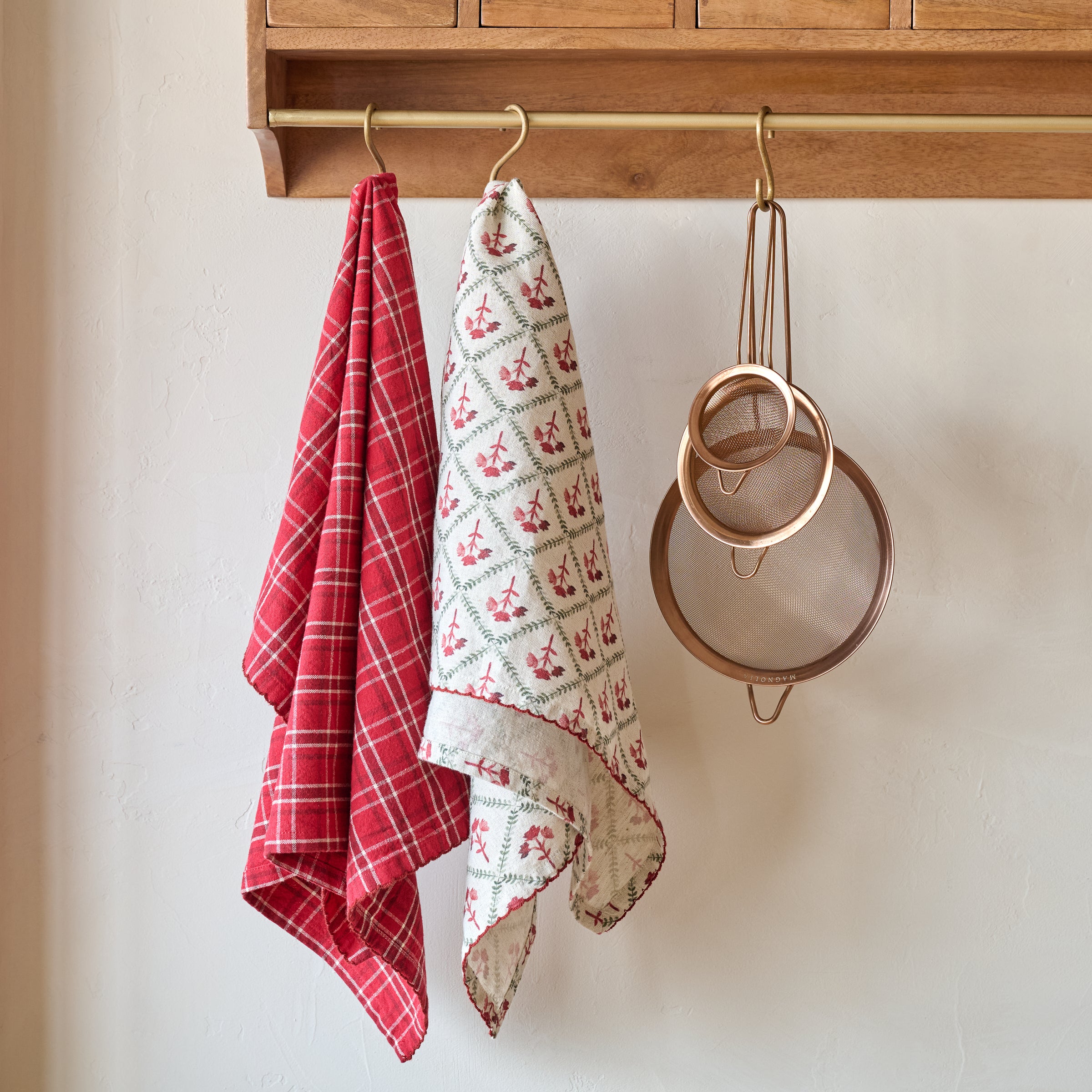 Magnoliass Vintage Red Plaid Tea Towel shown hung with other tea towel and kitchen utensils