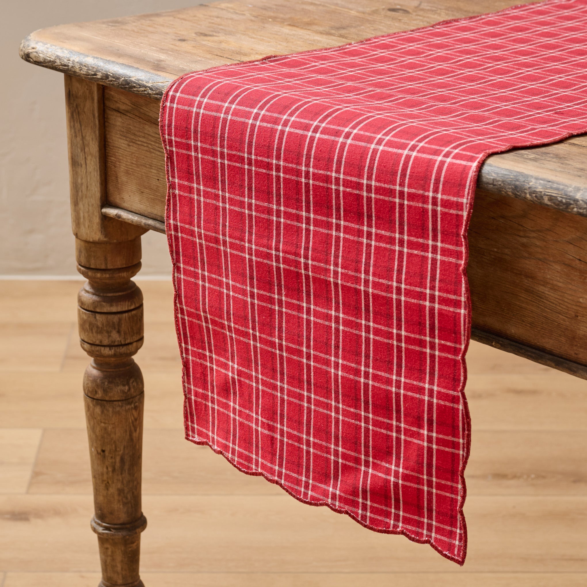 Magnoliass Festive Plaid Reversible Table Runner shown on table with red plaid side facing up