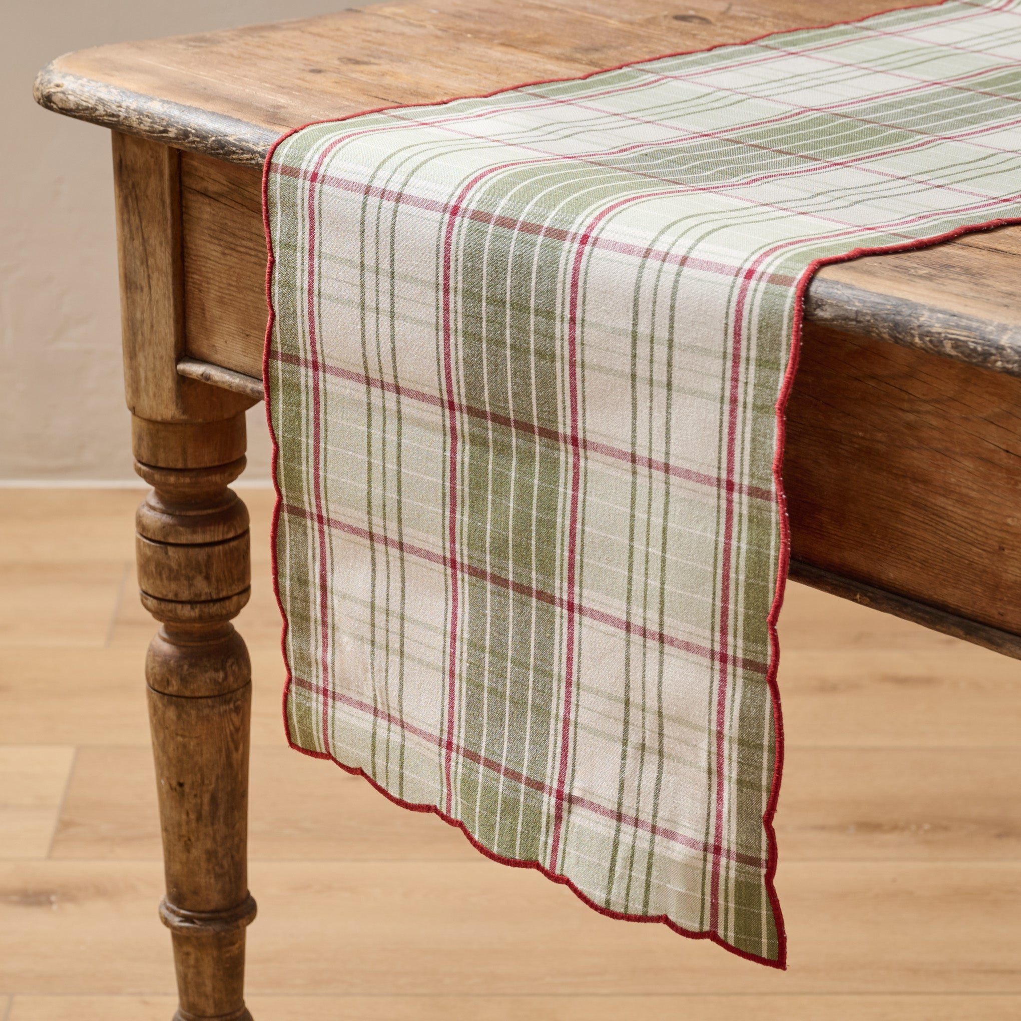 Magnoliass Festive Plaid Reversible Table Runner shown on table with green plaid side facing up
