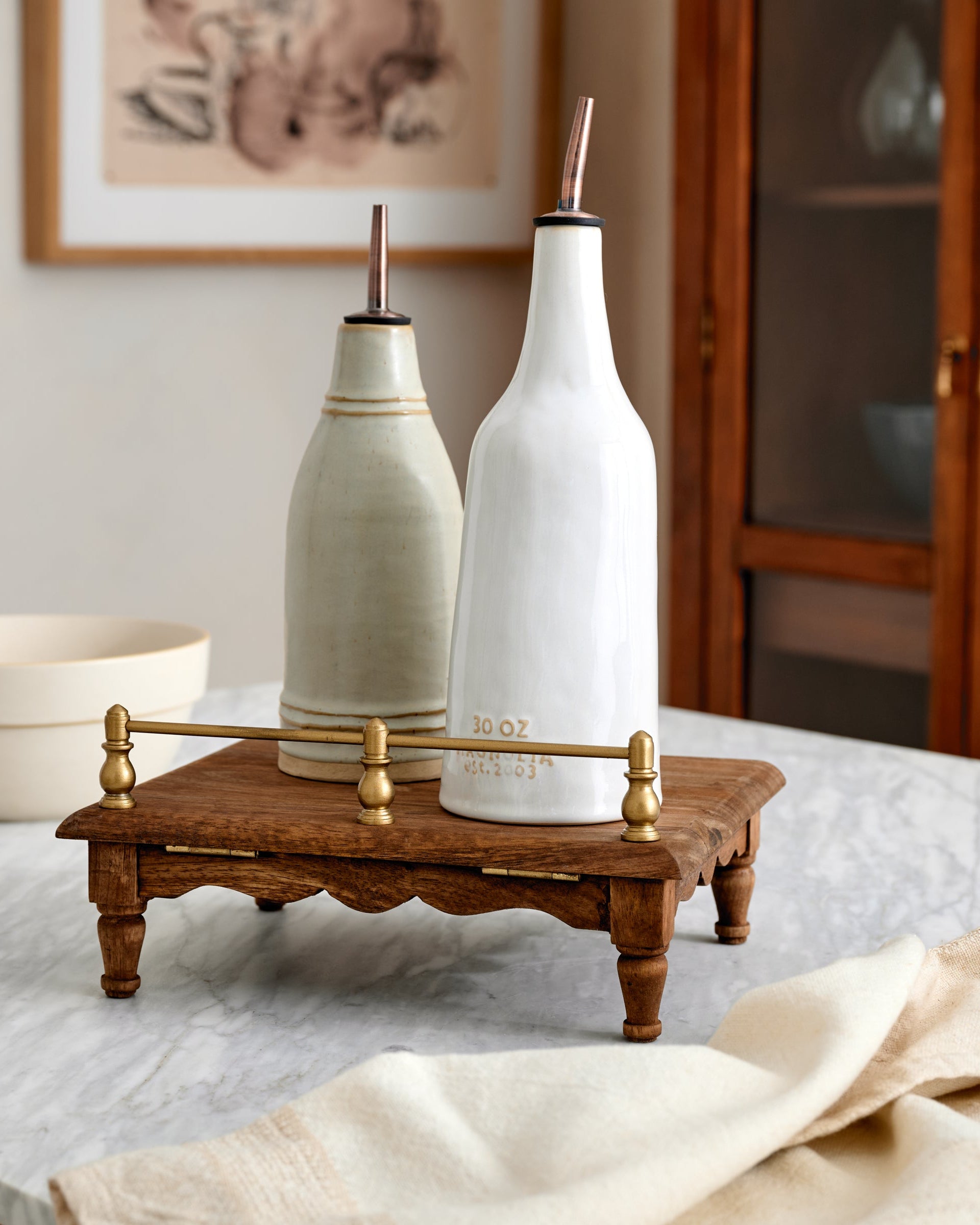 Vintage-Inspired Cookbook Holder + Riser shown as a riser with decorative kitchen tools holding oil or vinegar inside