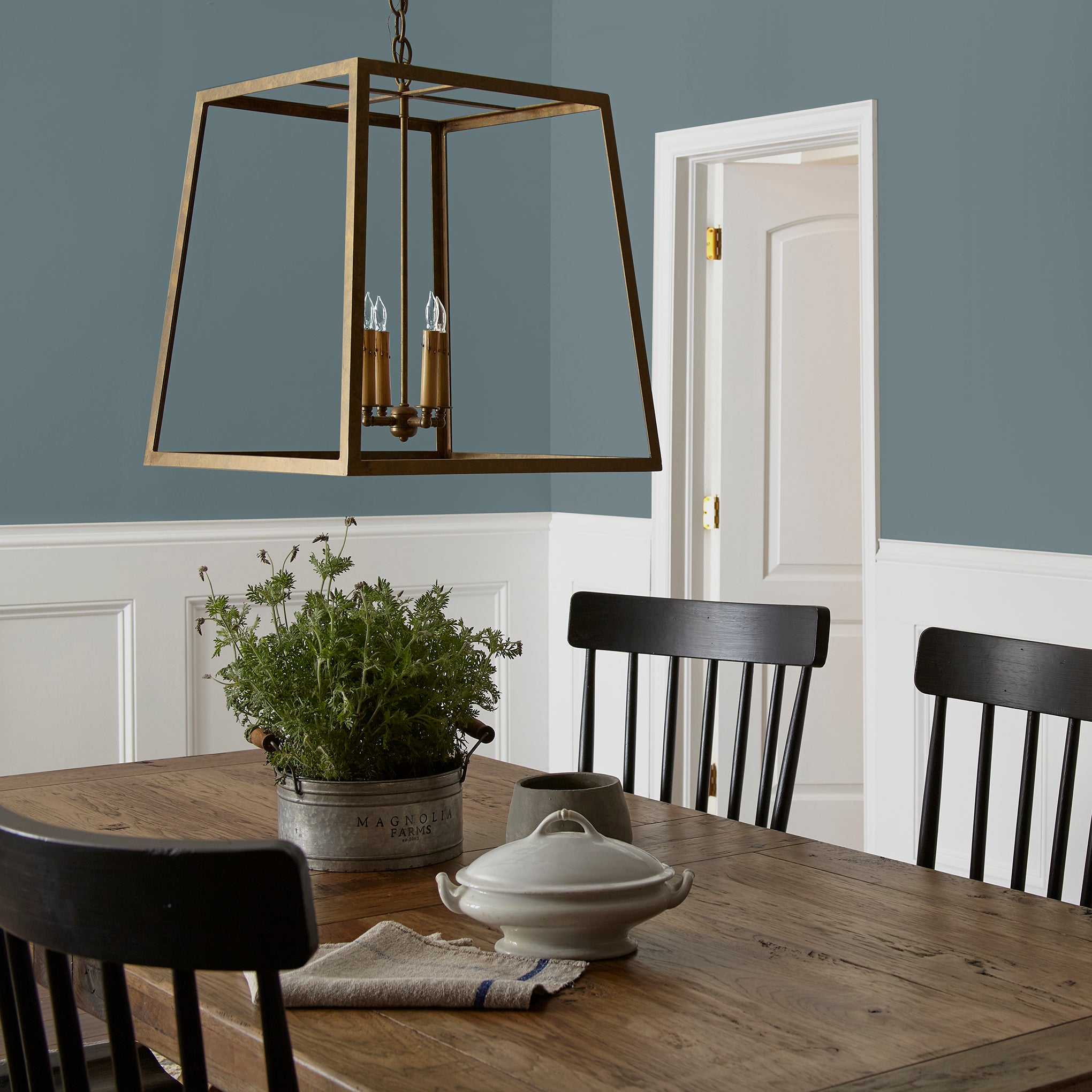 A grayed out blue interior paint named storm chaser shown painted on dining room wall 